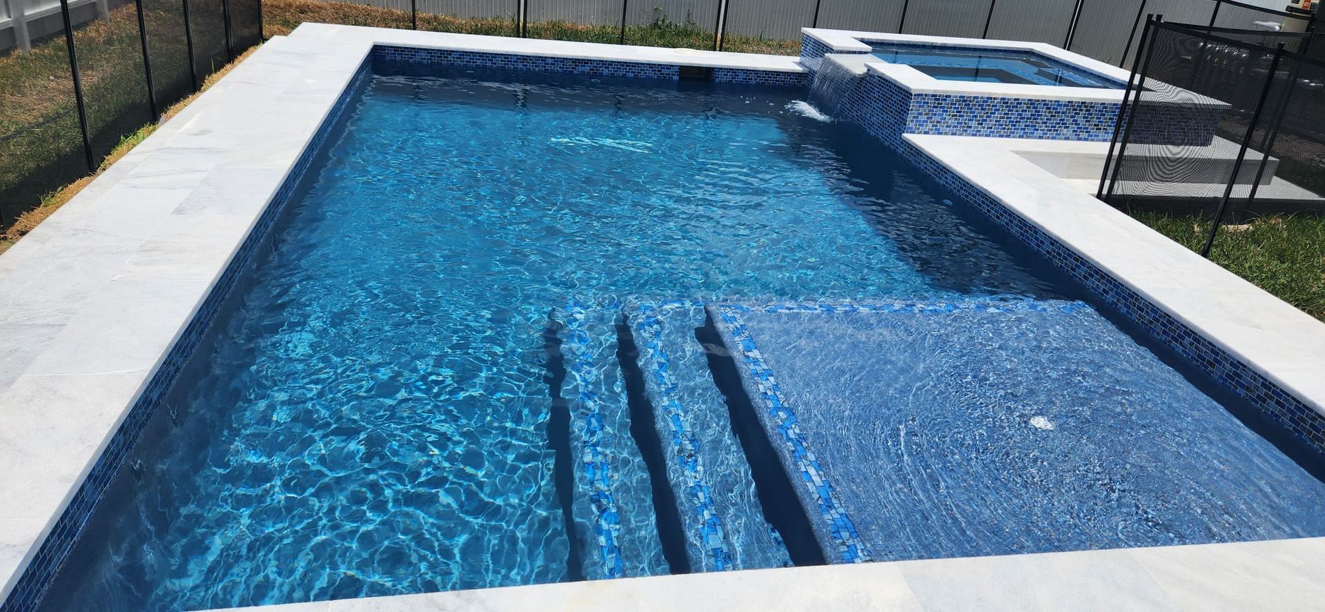 A large swimming pool with a hot tub in the backyard