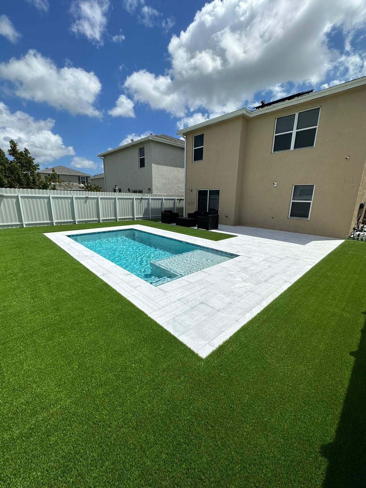 There is a large swimming pool in the backyard of a house.