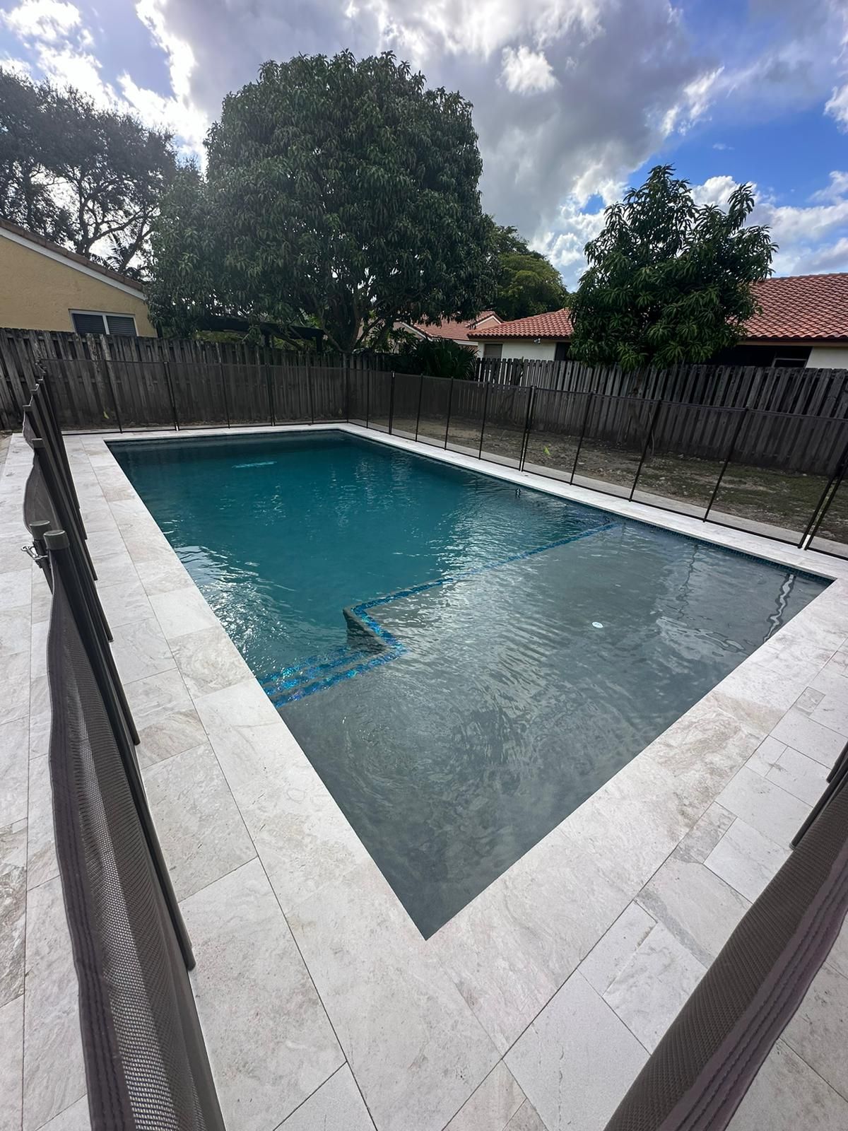 A large swimming pool surrounded by a fence in a backyard.