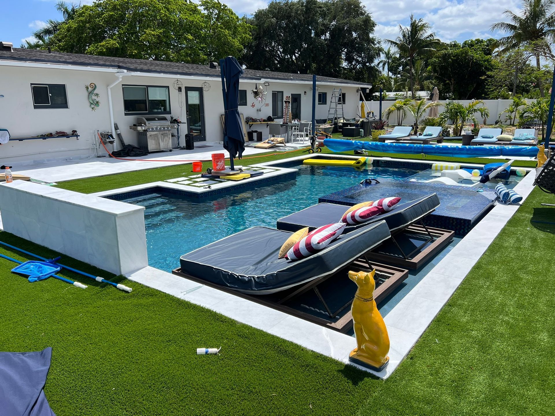 A large swimming pool is surrounded by lawn chairs and umbrellas.