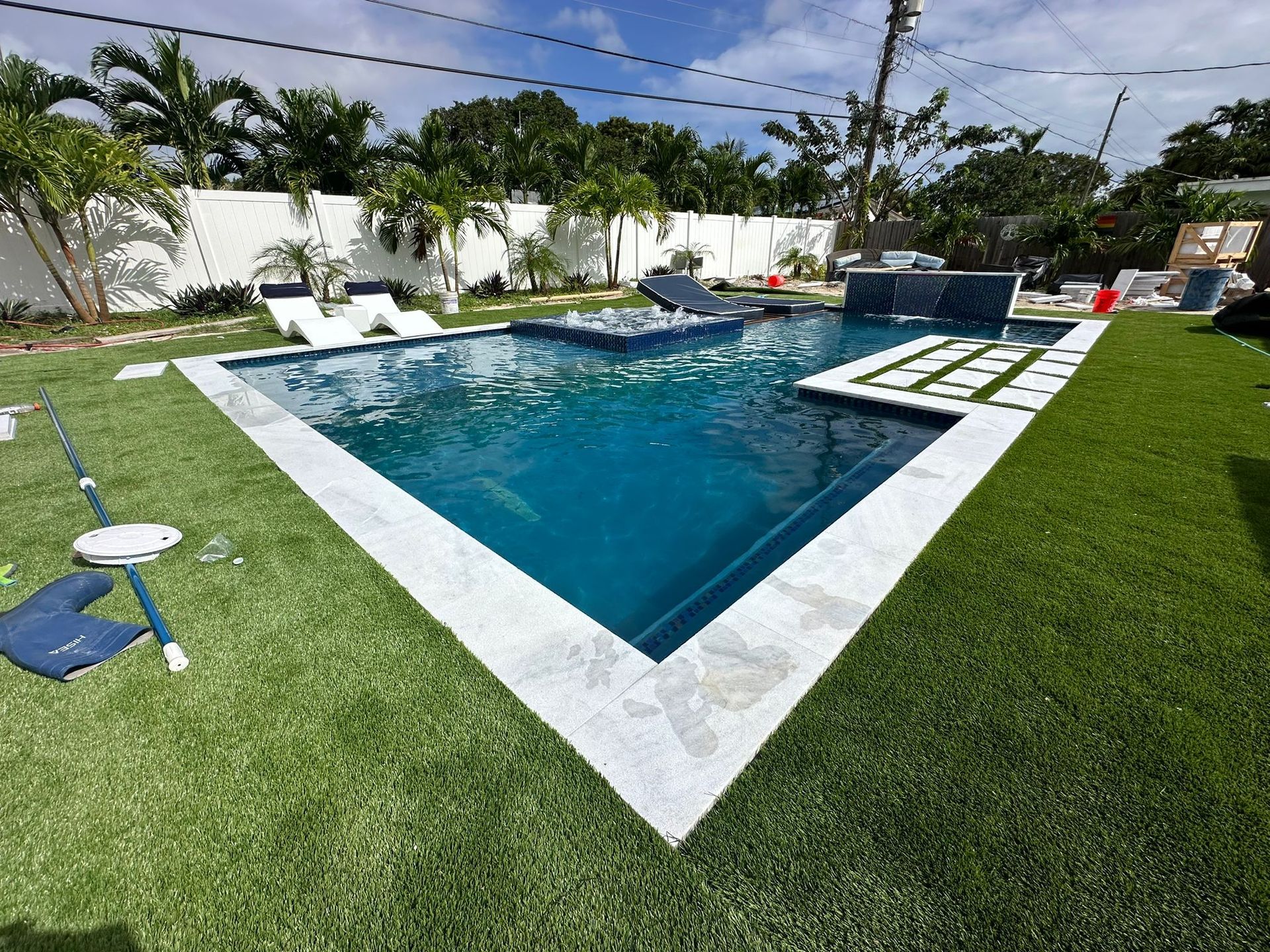 A large swimming pool is surrounded by a lush green lawn.