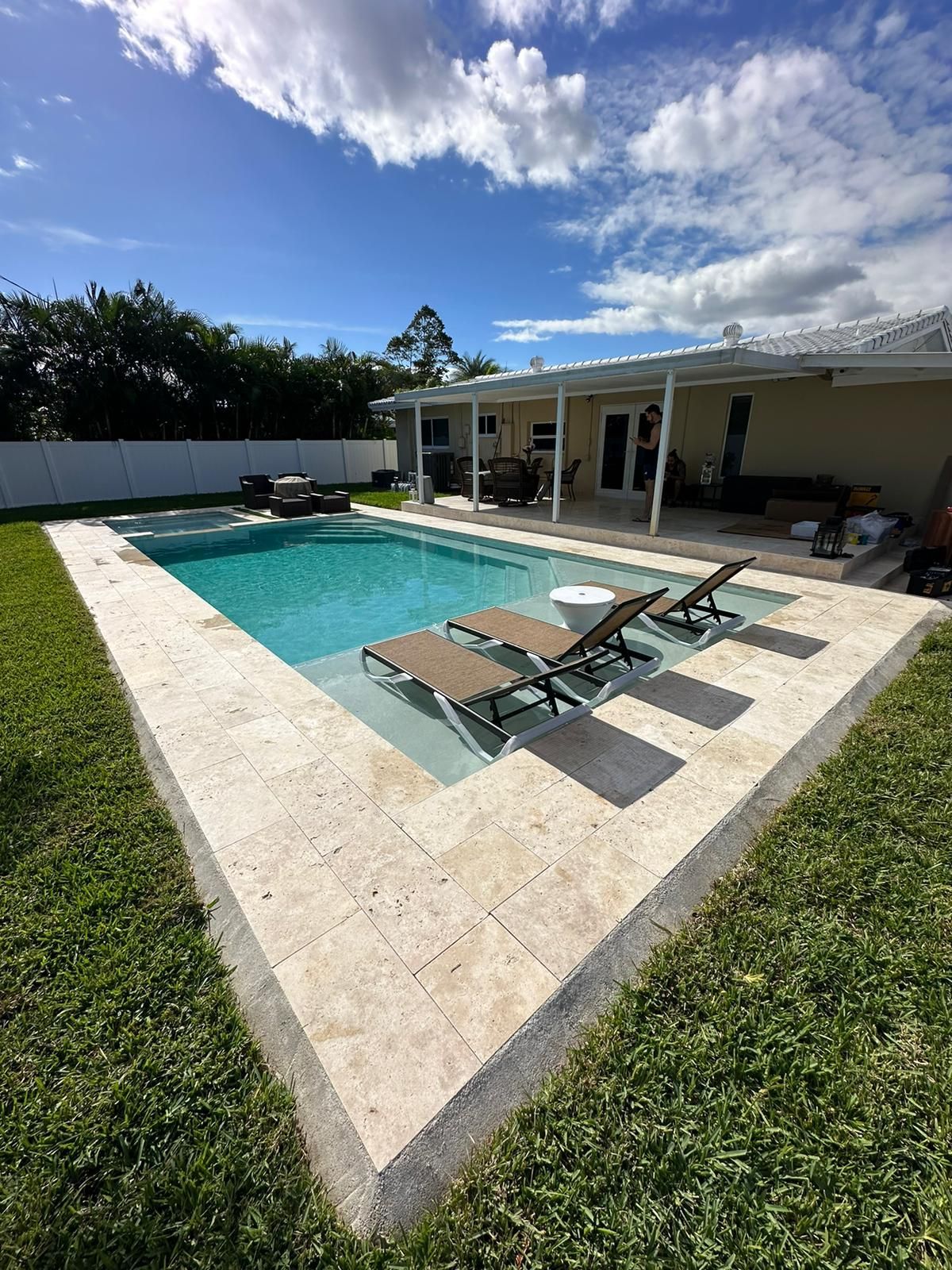 There is a large swimming pool in the backyard of a house.