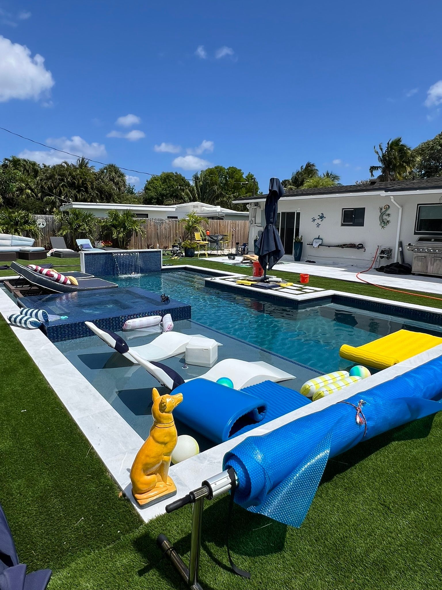 There is a large swimming pool in the backyard of a house.