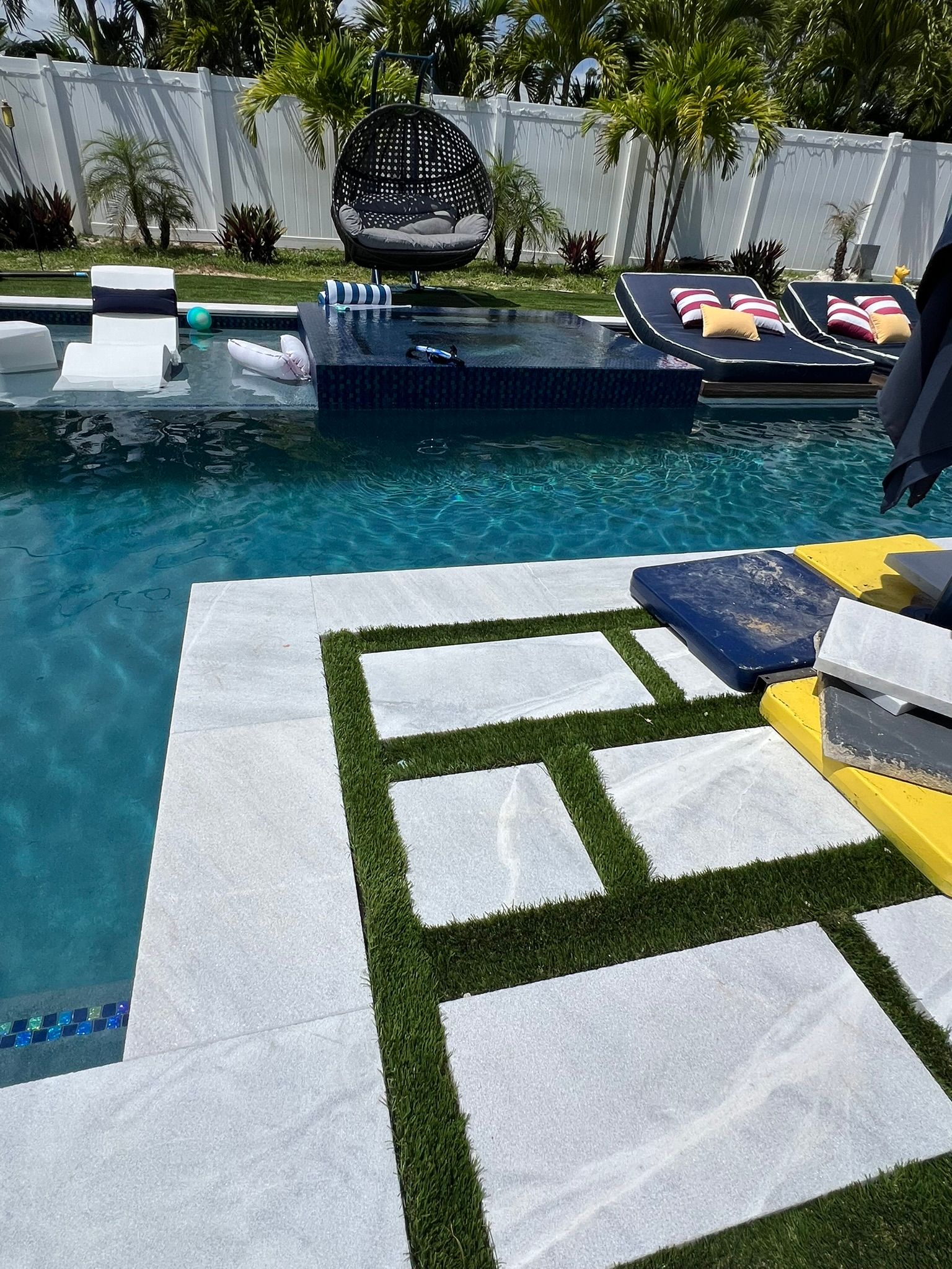 A large swimming pool surrounded by lawn chairs and umbrellas.