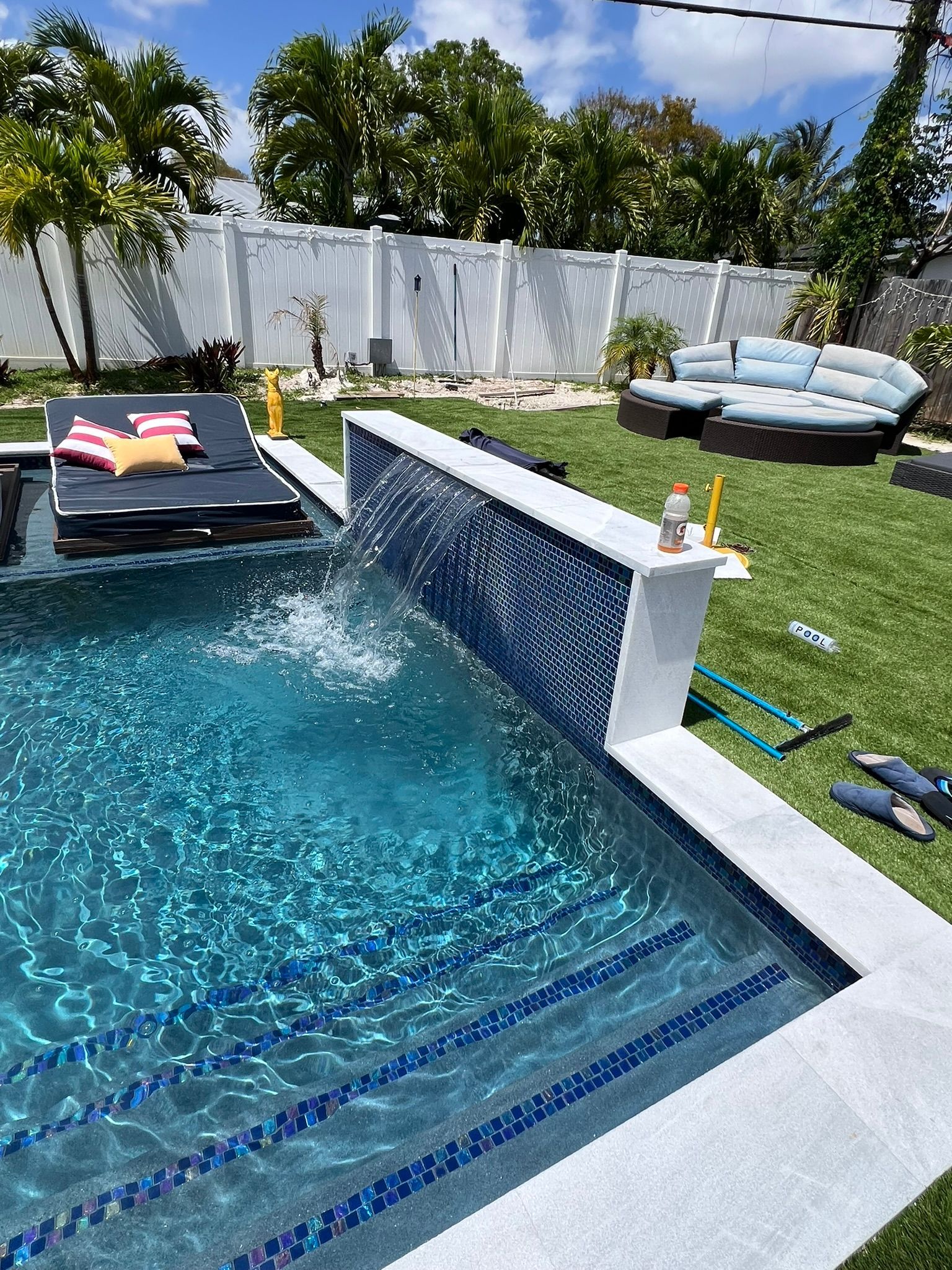 A large swimming pool with a waterfall in the backyard.