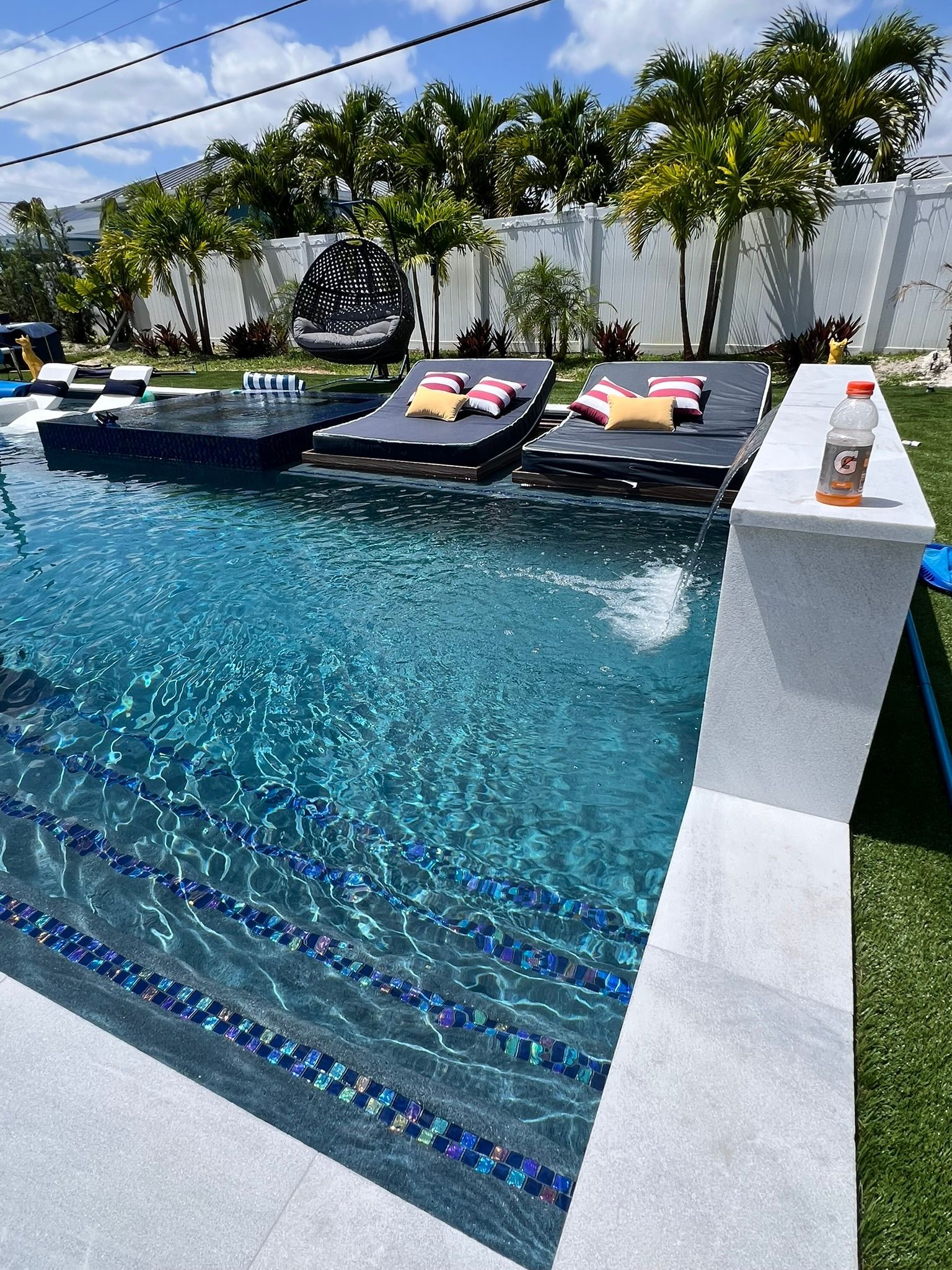 A large swimming pool with a bar and lounge chairs in the backyard.