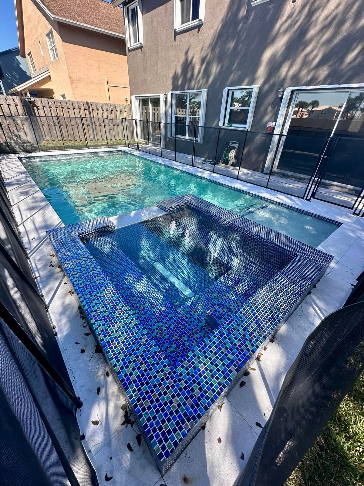 A large swimming pool with a hot tub in the middle of it.