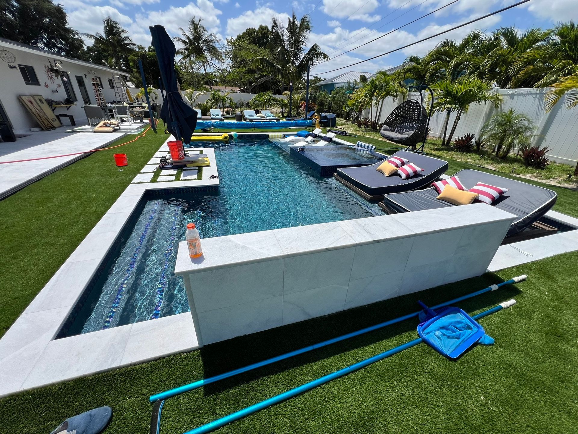 A large swimming pool is surrounded by lawn chairs and umbrellas.