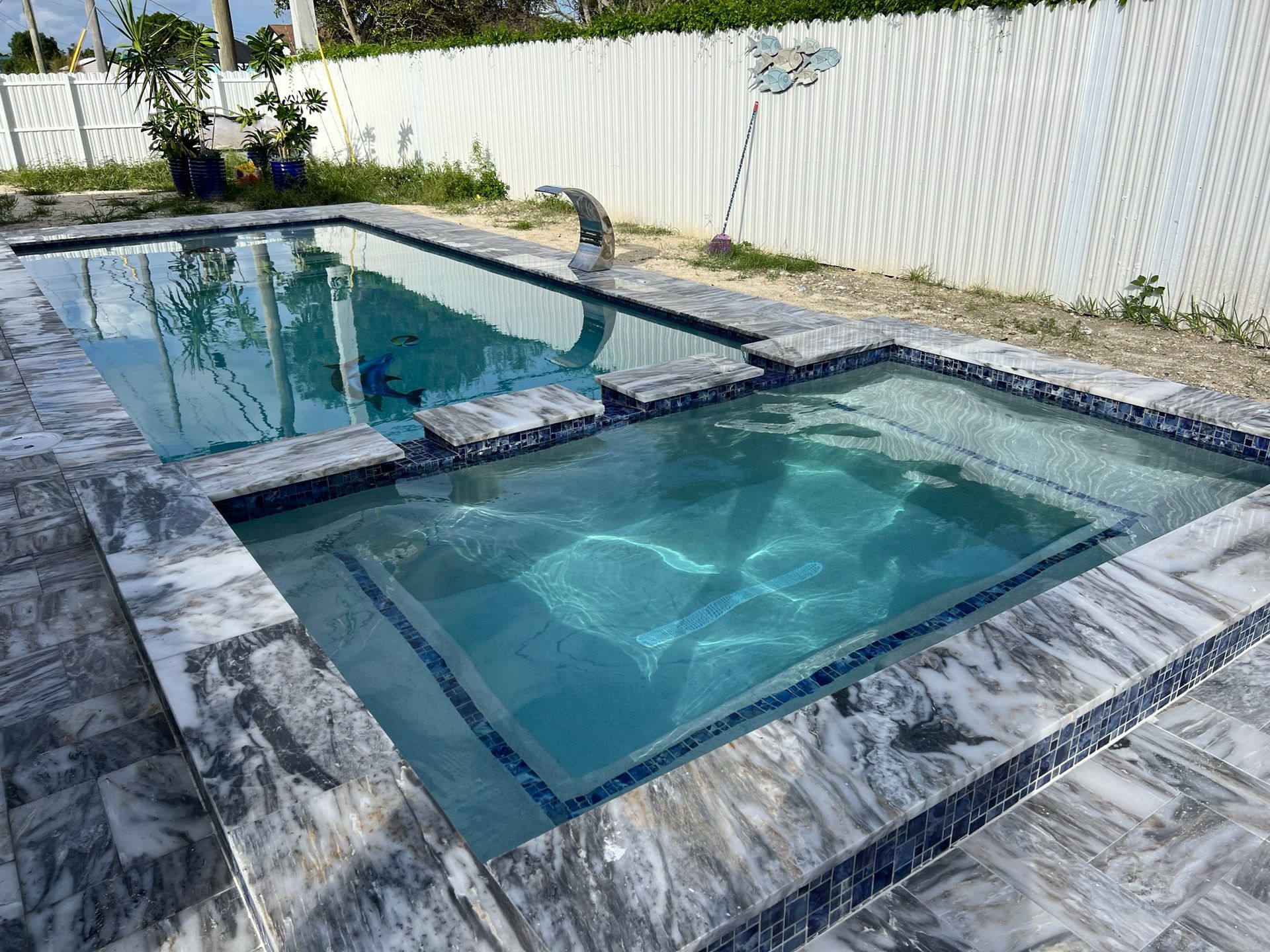 A large swimming pool with a dolphin fountain in the middle of it.