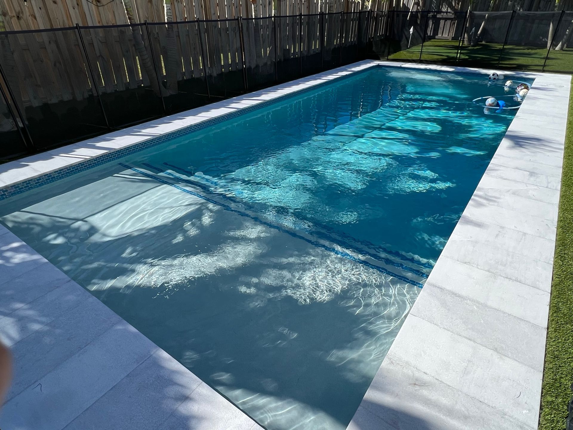 A large swimming pool filled with blue water in a backyard.