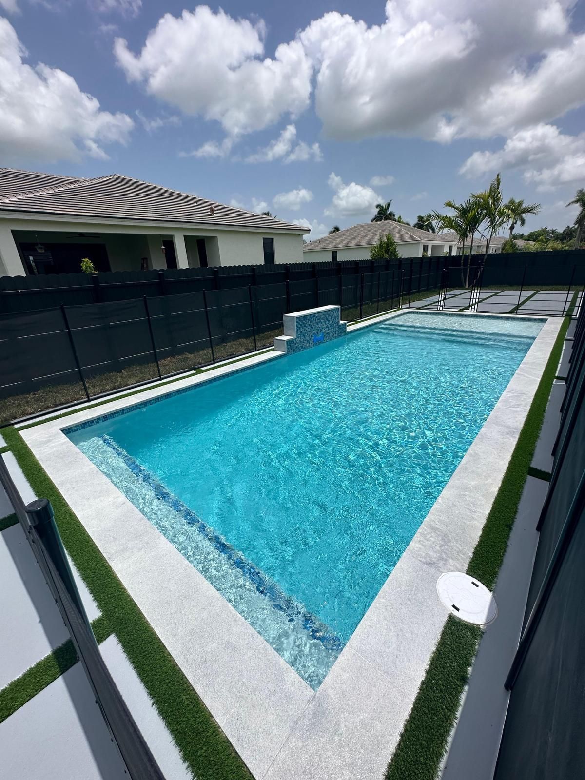 A large swimming pool in the backyard of a house.