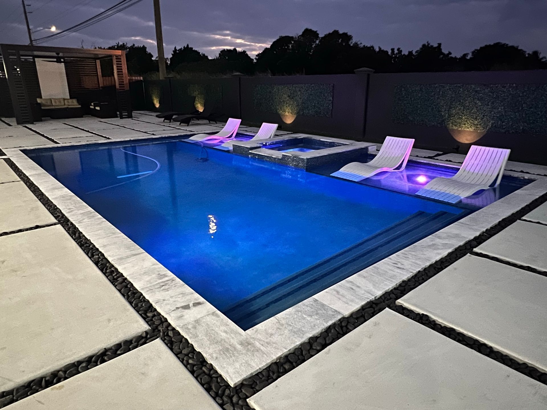 A large swimming pool with chairs around it at night