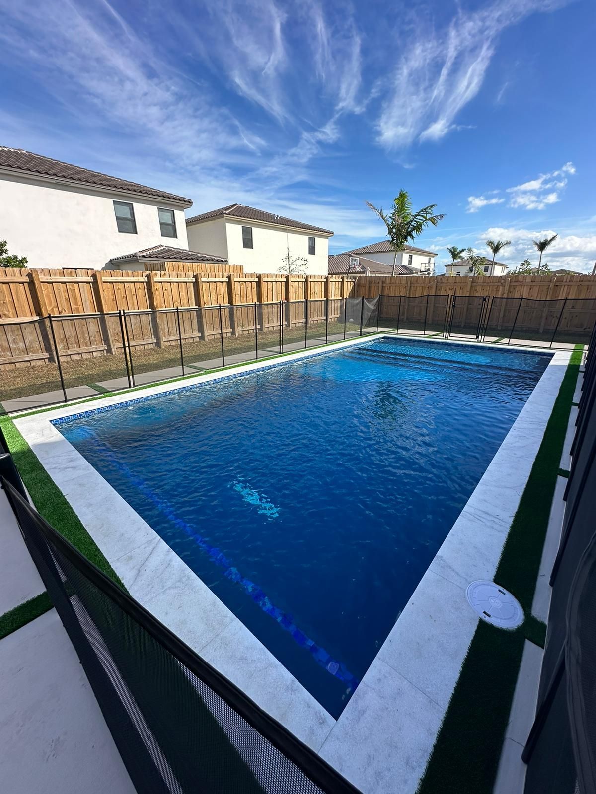 A large swimming pool surrounded by a fence in a backyard.