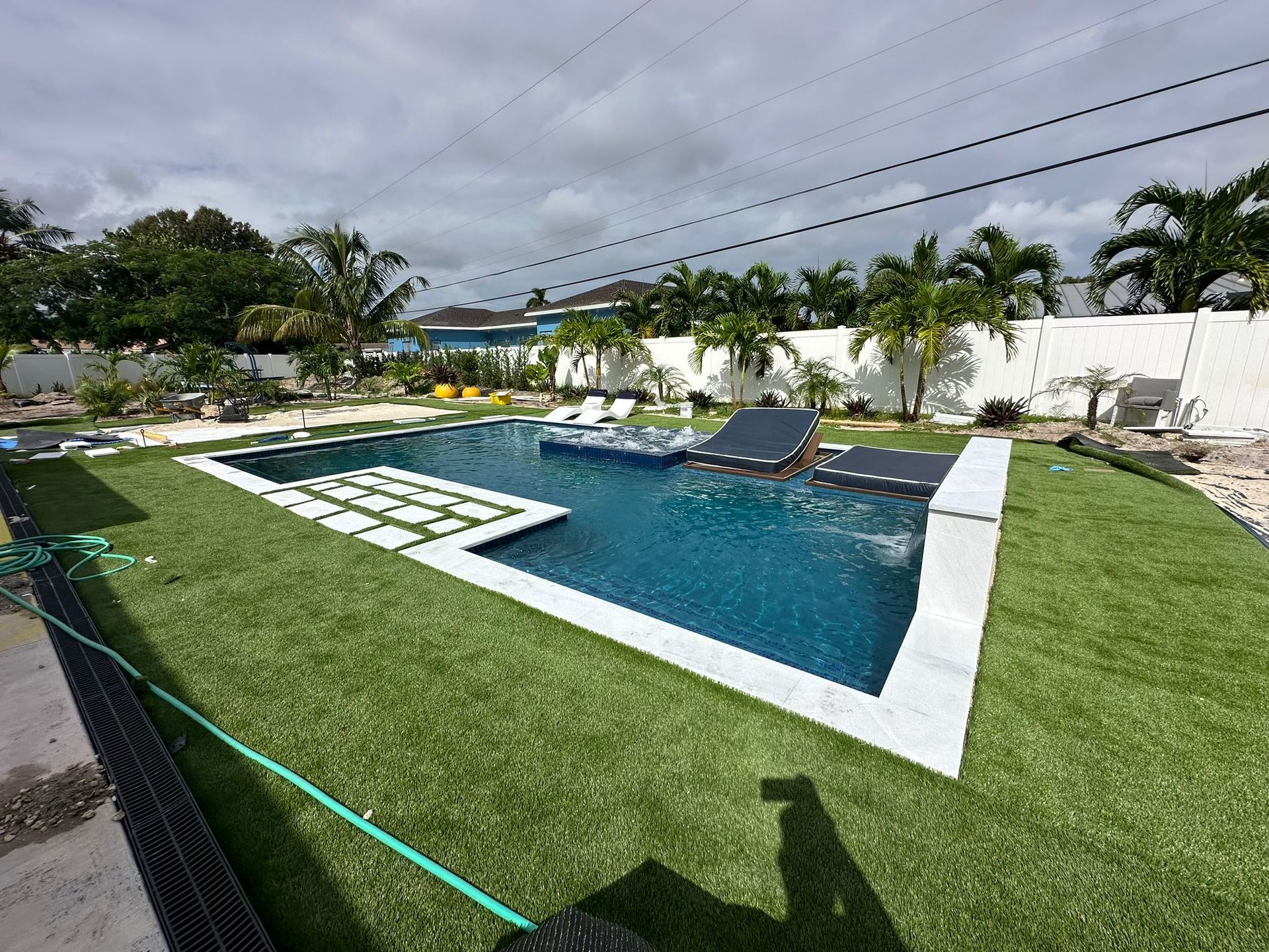 A large swimming pool is surrounded by a lush green lawn.