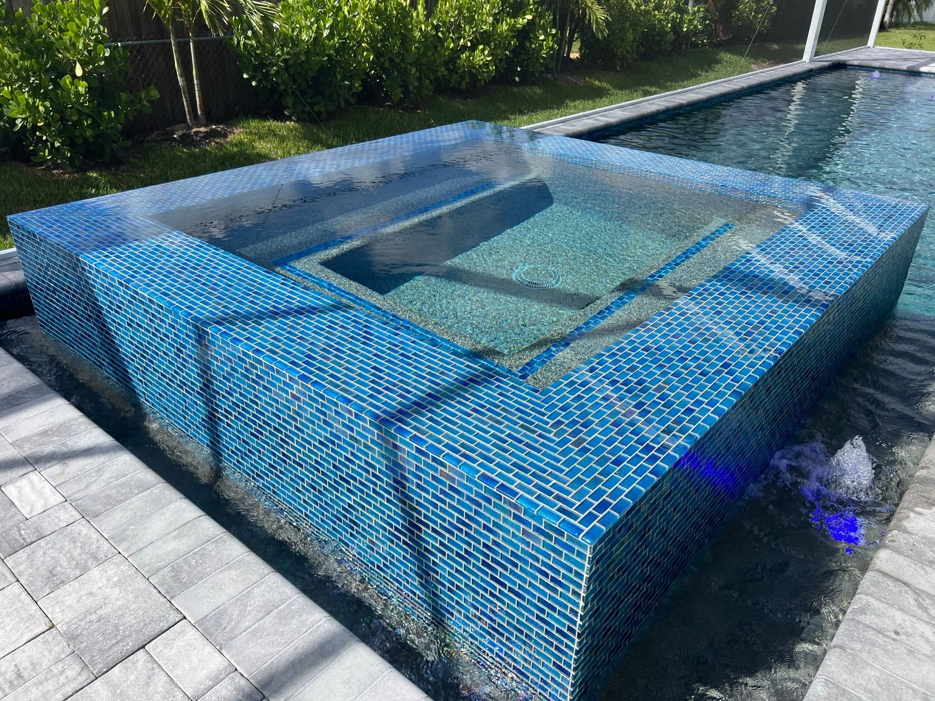 A large swimming pool with a hot tub in the middle of it.