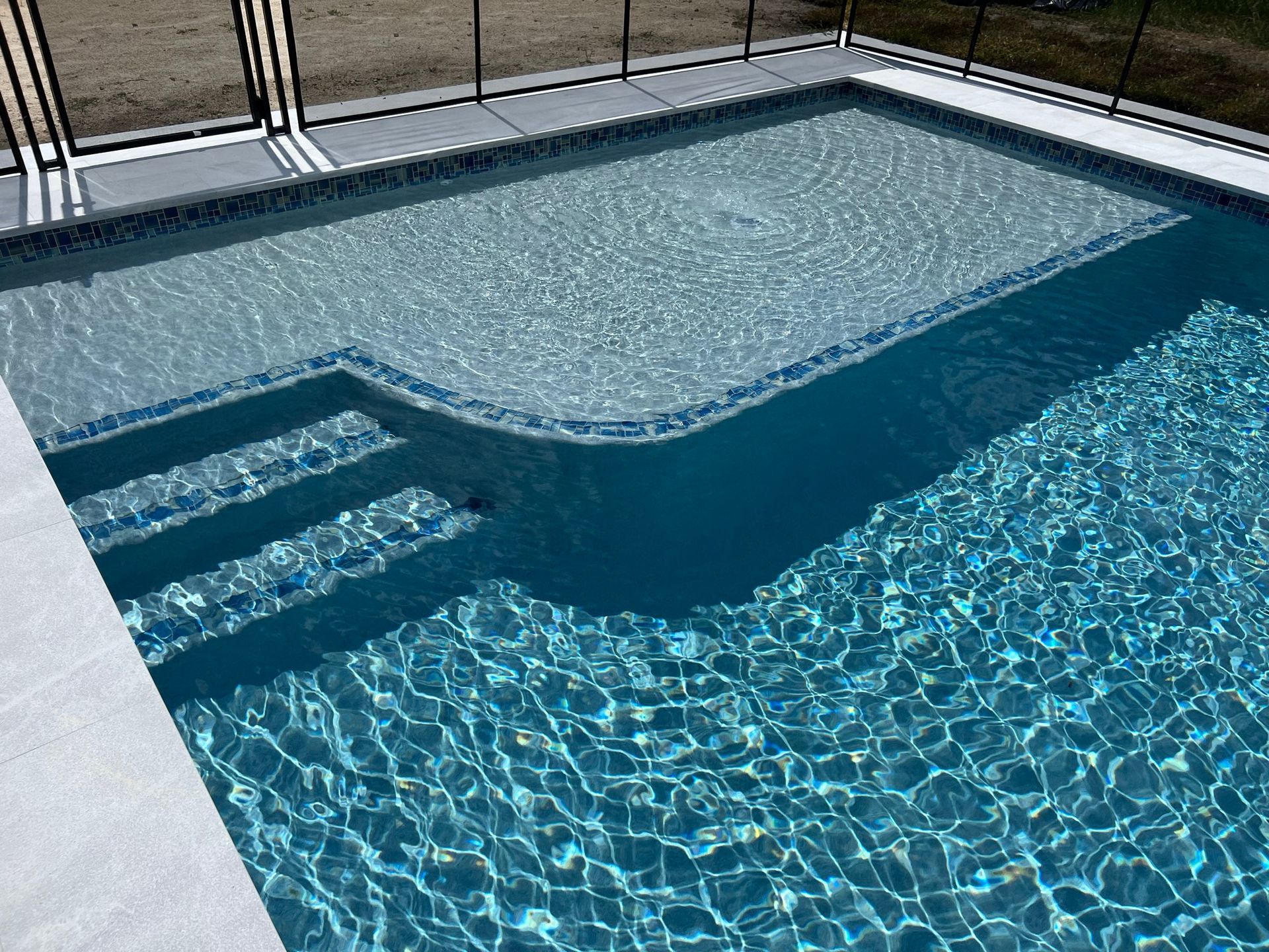 A large swimming pool with stairs and a fence surrounding it.
