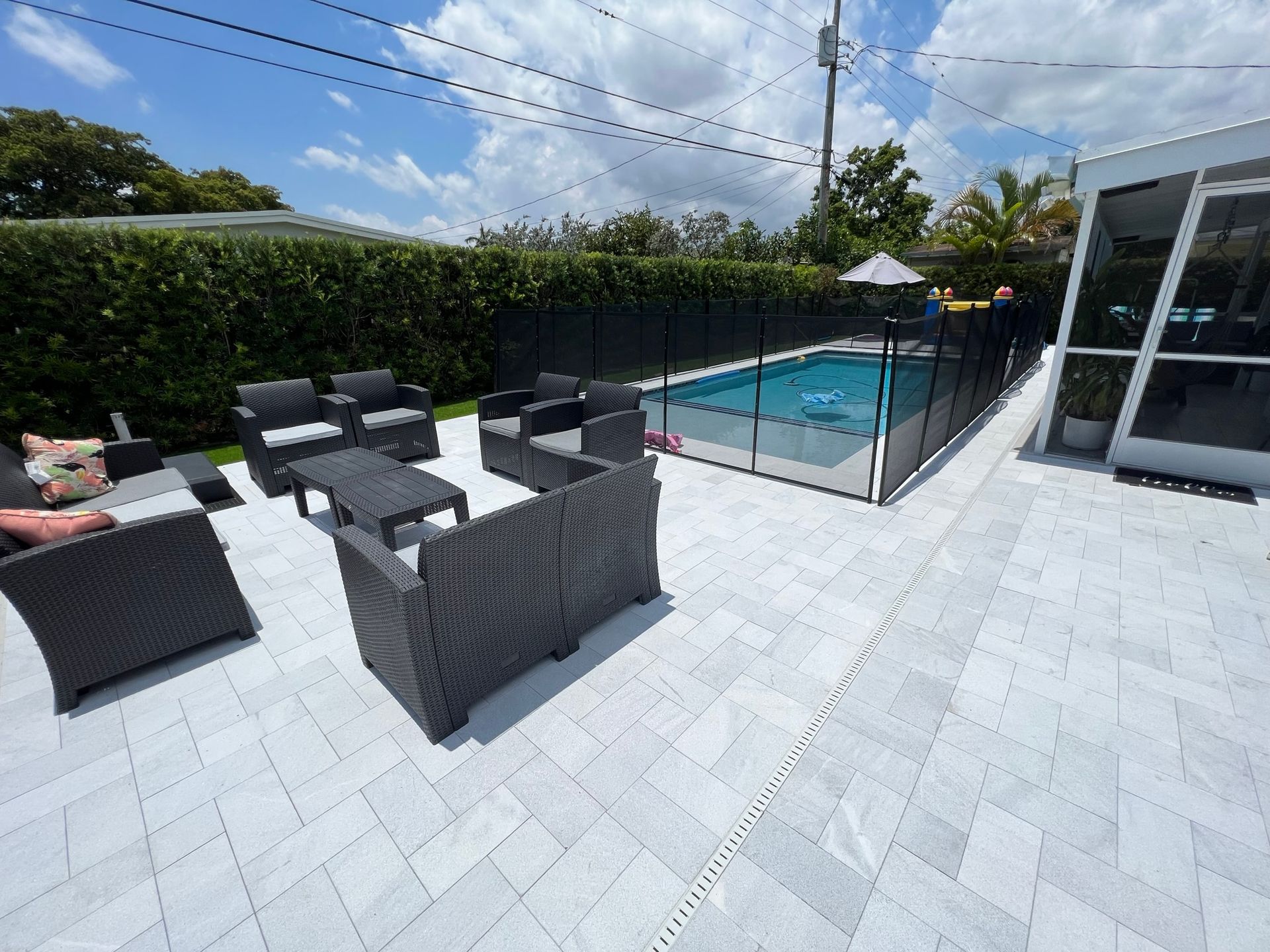A patio with furniture and a pool in the background