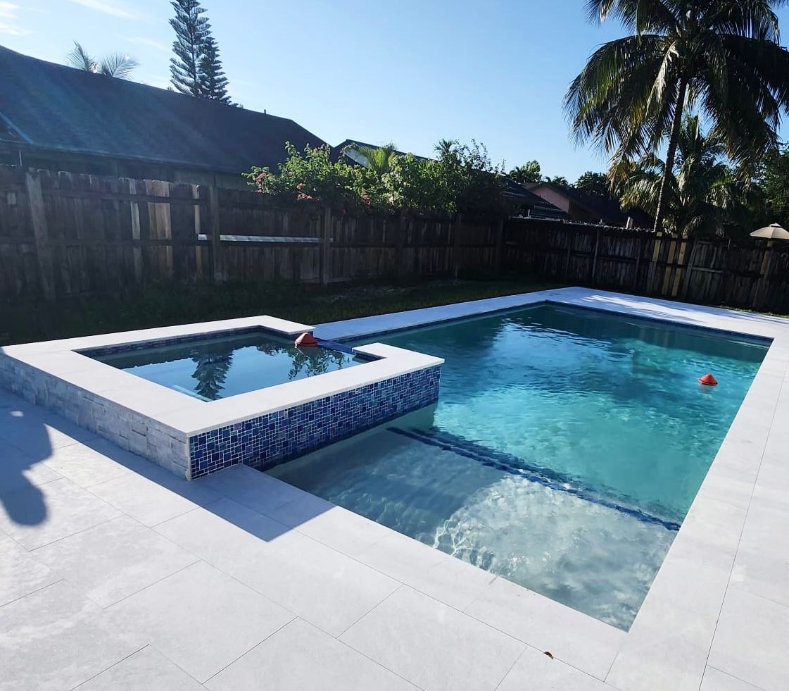 A large swimming pool with a hot tub in the backyard