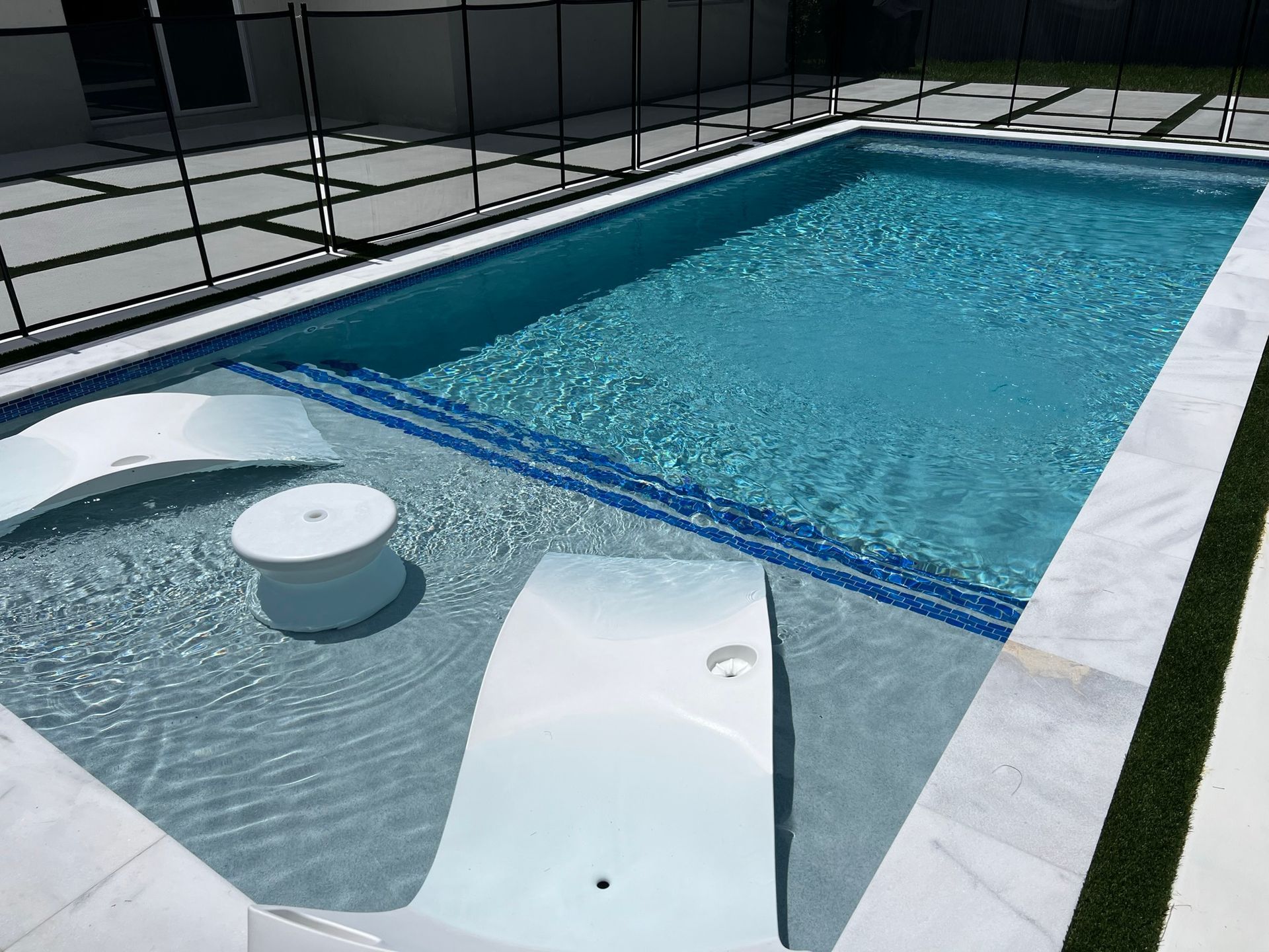 A large swimming pool with chairs and a table in it.