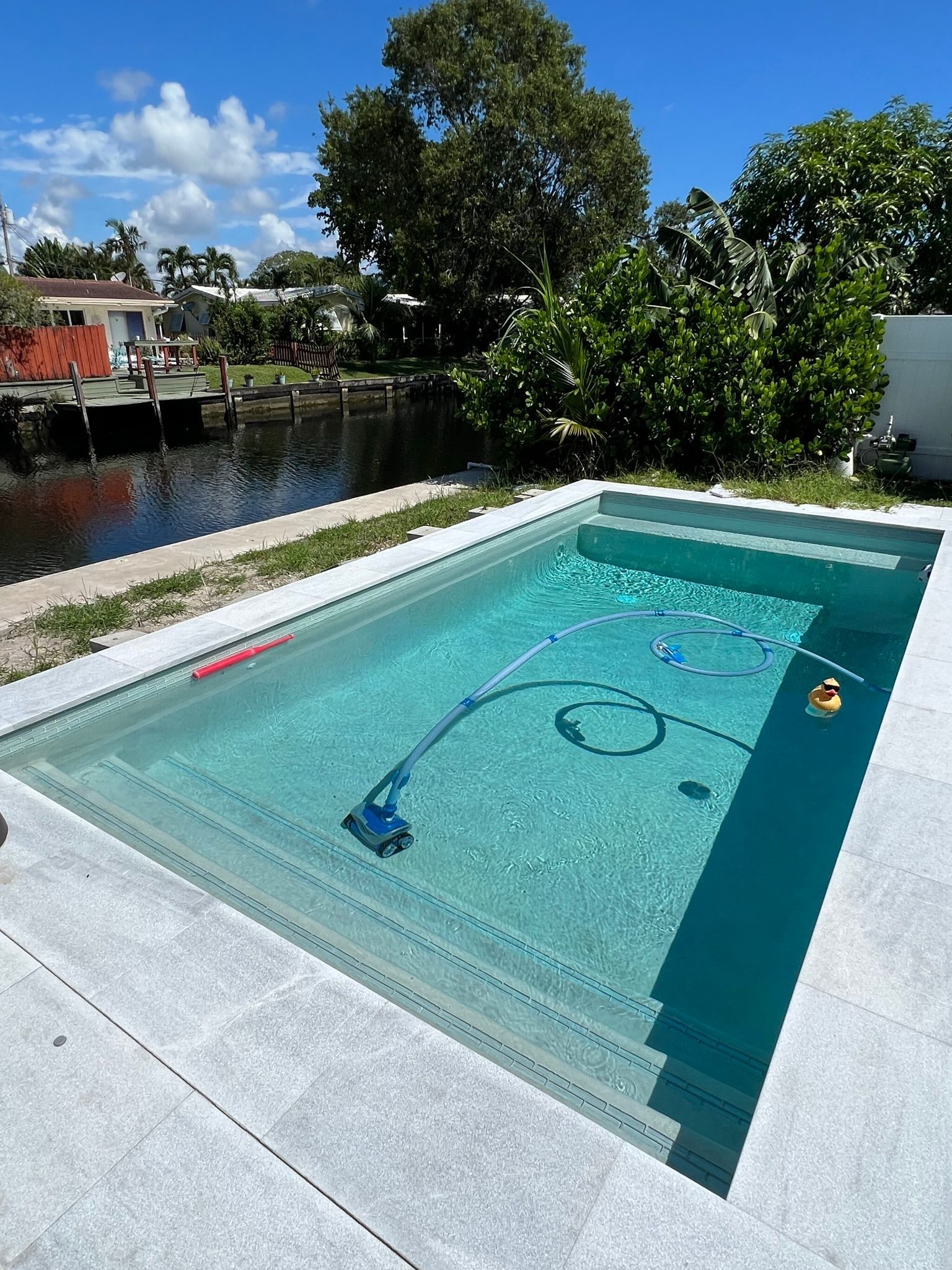 A large swimming pool with a vacuum cleaner in it is next to a river.