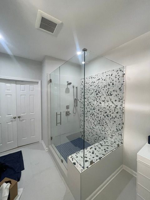Modern white bathroom with glass shower enclosure and mosaic tile accent wall