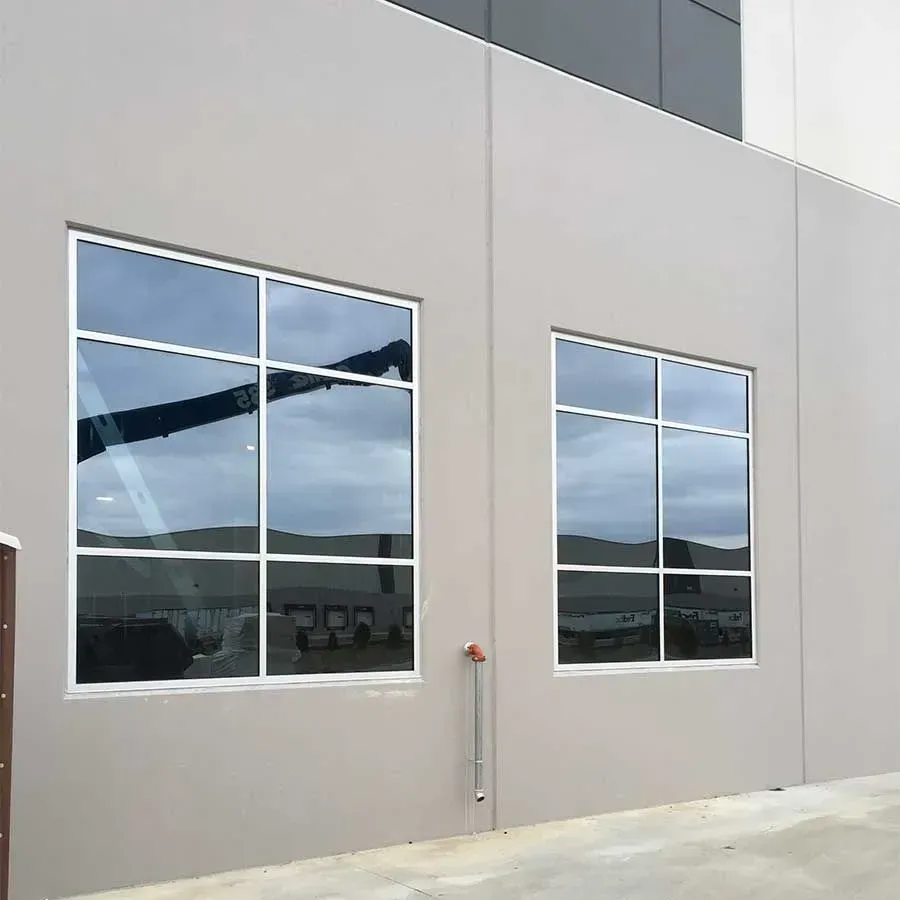 Two rectangular glass windows with white frames on a beige exterior wall of a modern building.