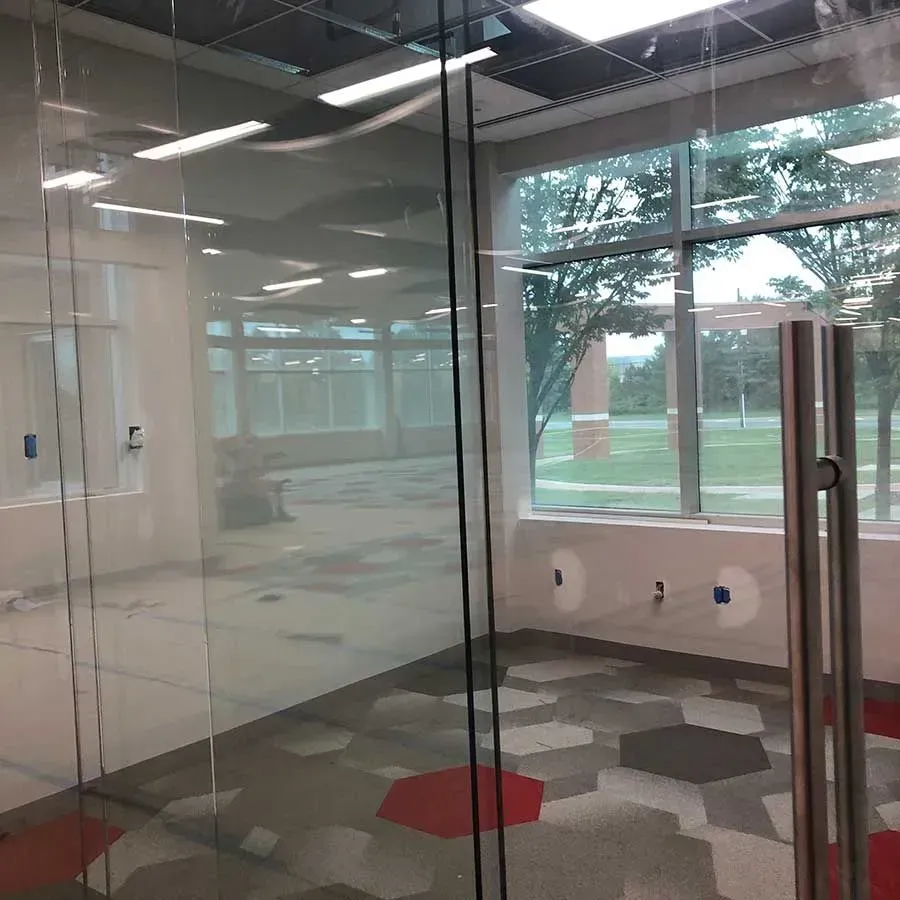 Glass-walled office space featuring a geometric patterned carpet with grey, brown, and red hexagonal shapes.