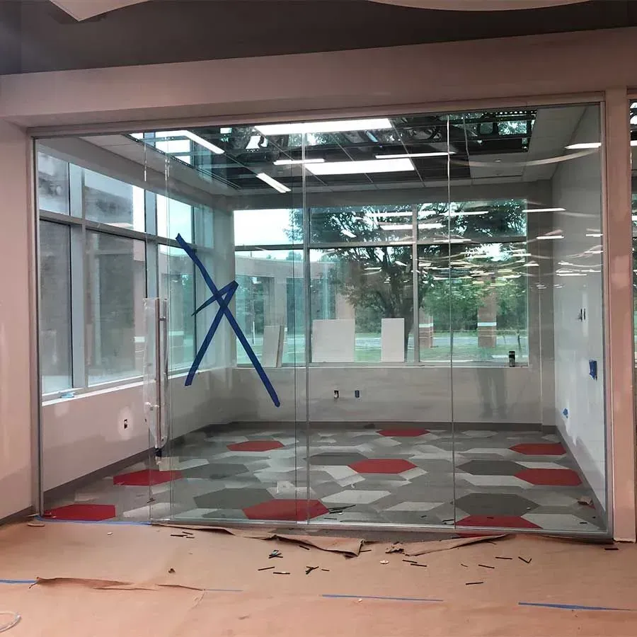 A glass-walled office under construction with a patterned floor featuring red and grey hexagon tiles.