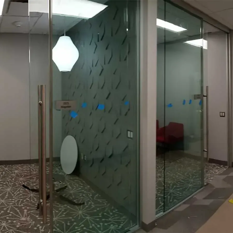 Modern office meeting rooms with glass walls, geometric-patterned dark walls, white pendant lighting, and patterned carpet.
