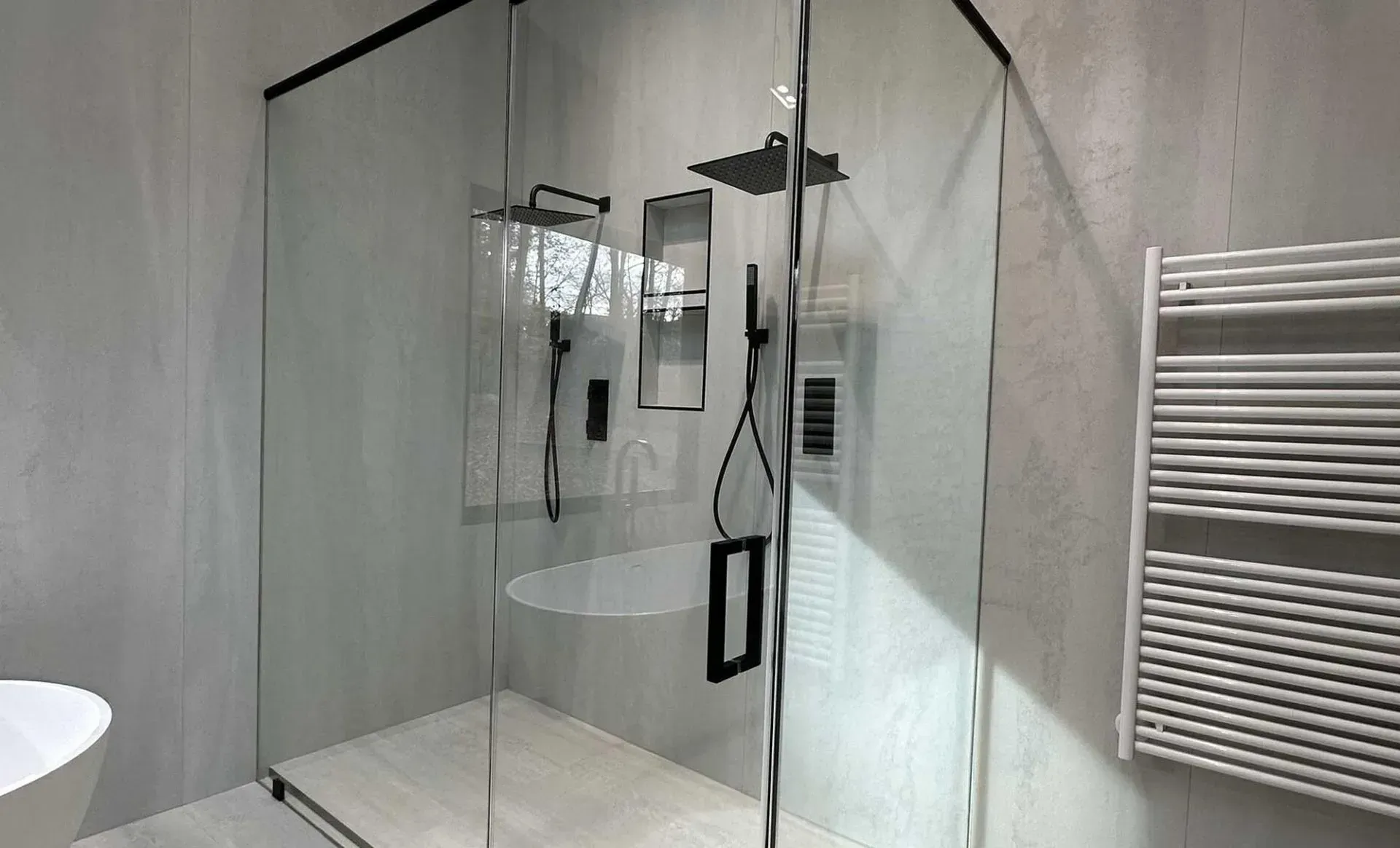 A modern bathroom featuring a glass-enclosed shower with black fixtures and a white towel warmer on the adjacent wall.
