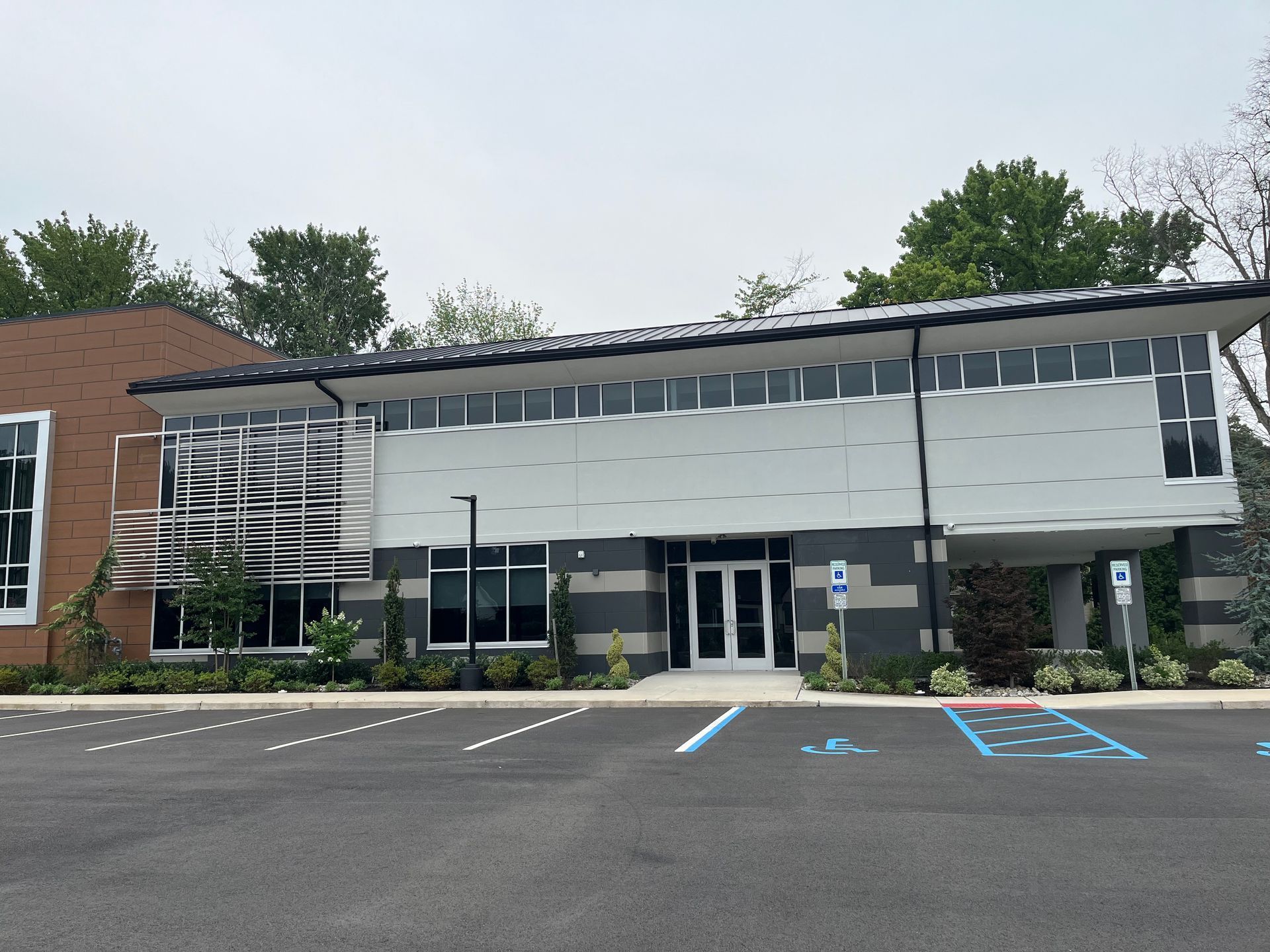 Modern office building with glass entrance, brick wing, and empty parking lot