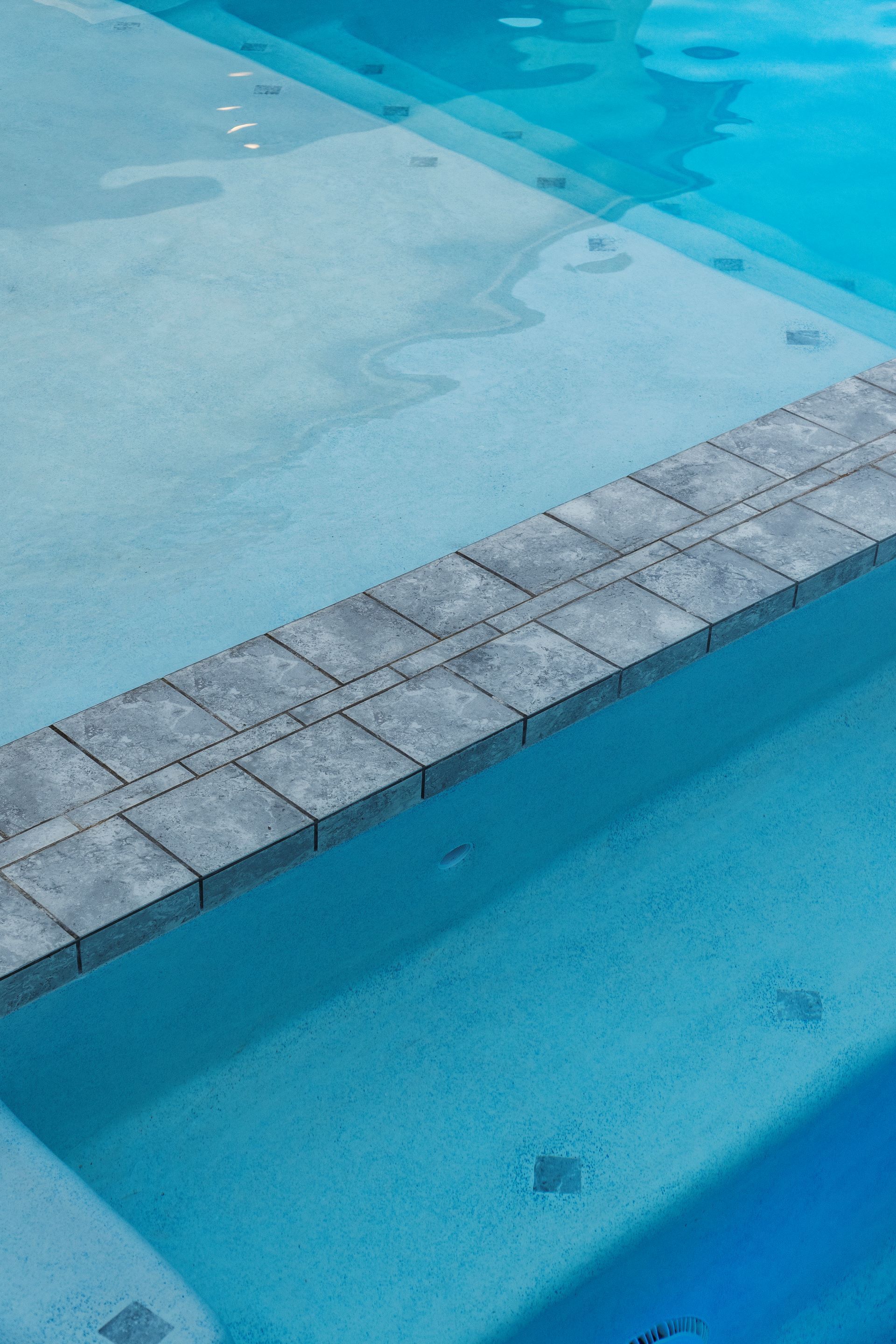 A swimming pool with a brick border and steps leading into it.