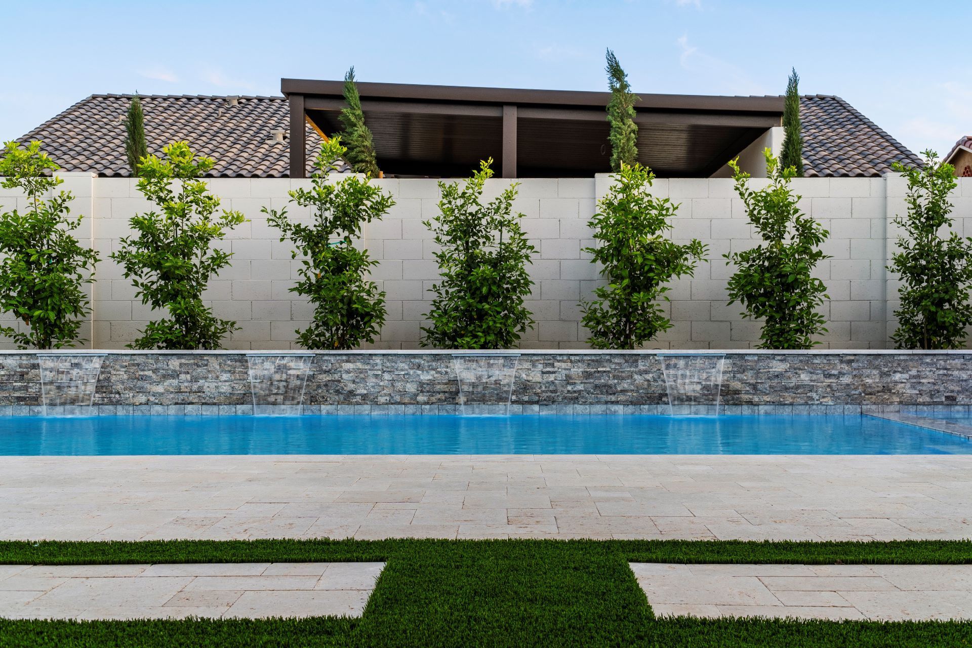 A large swimming pool with a waterfall in the backyard of a house