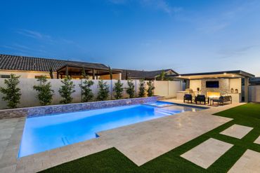 A patio with chairs and a table in front of a swimming pool