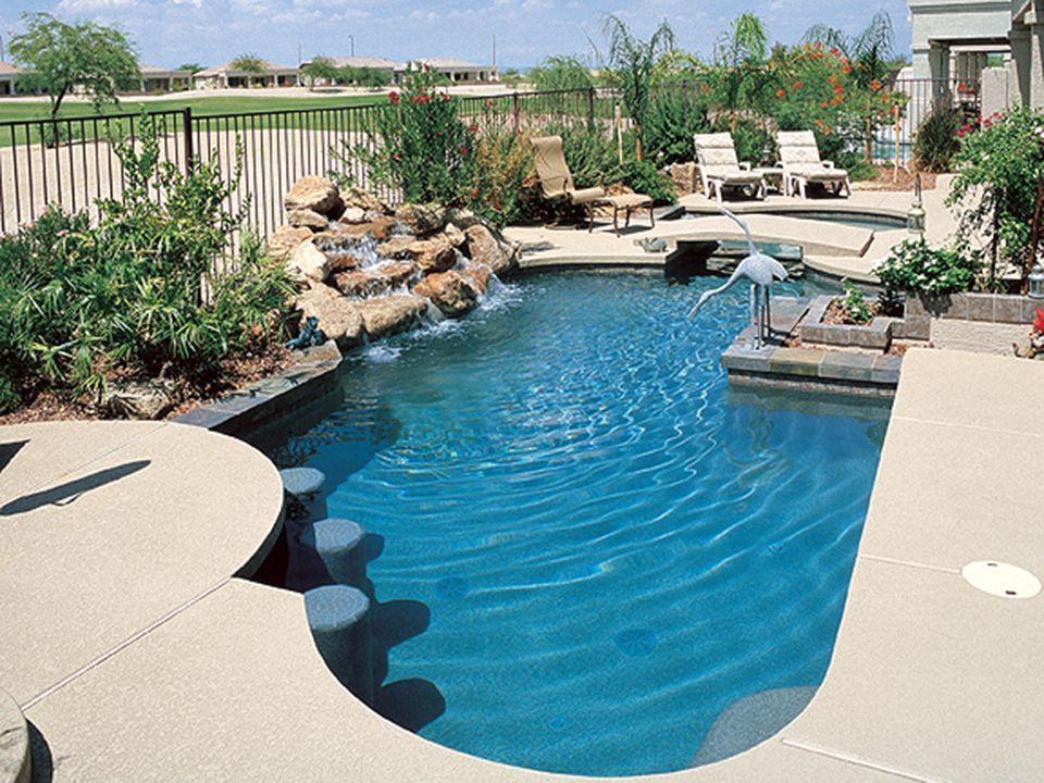 A large swimming pool with a waterfall in the backyard
