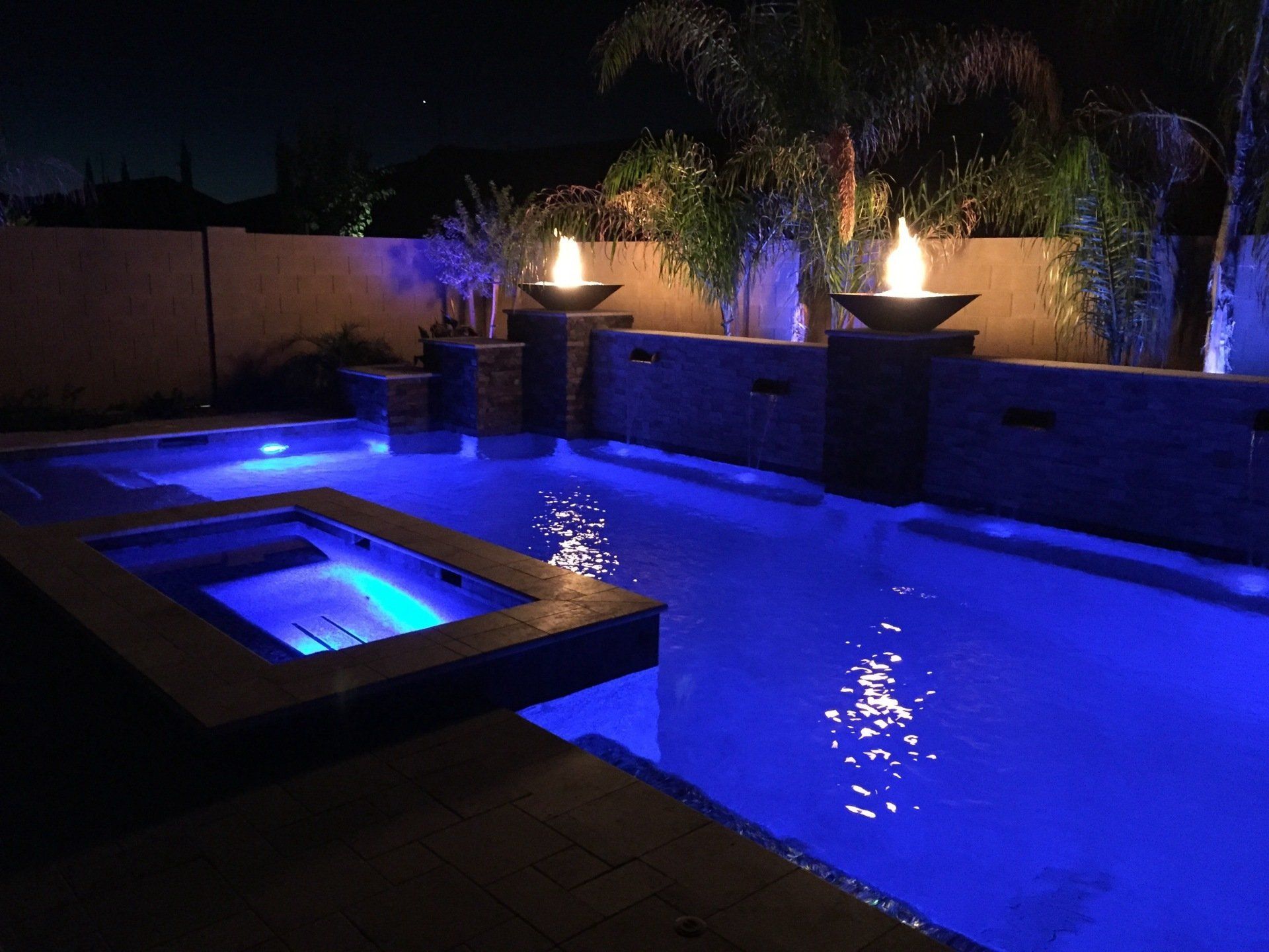 A swimming pool is lit up at night with blue lights