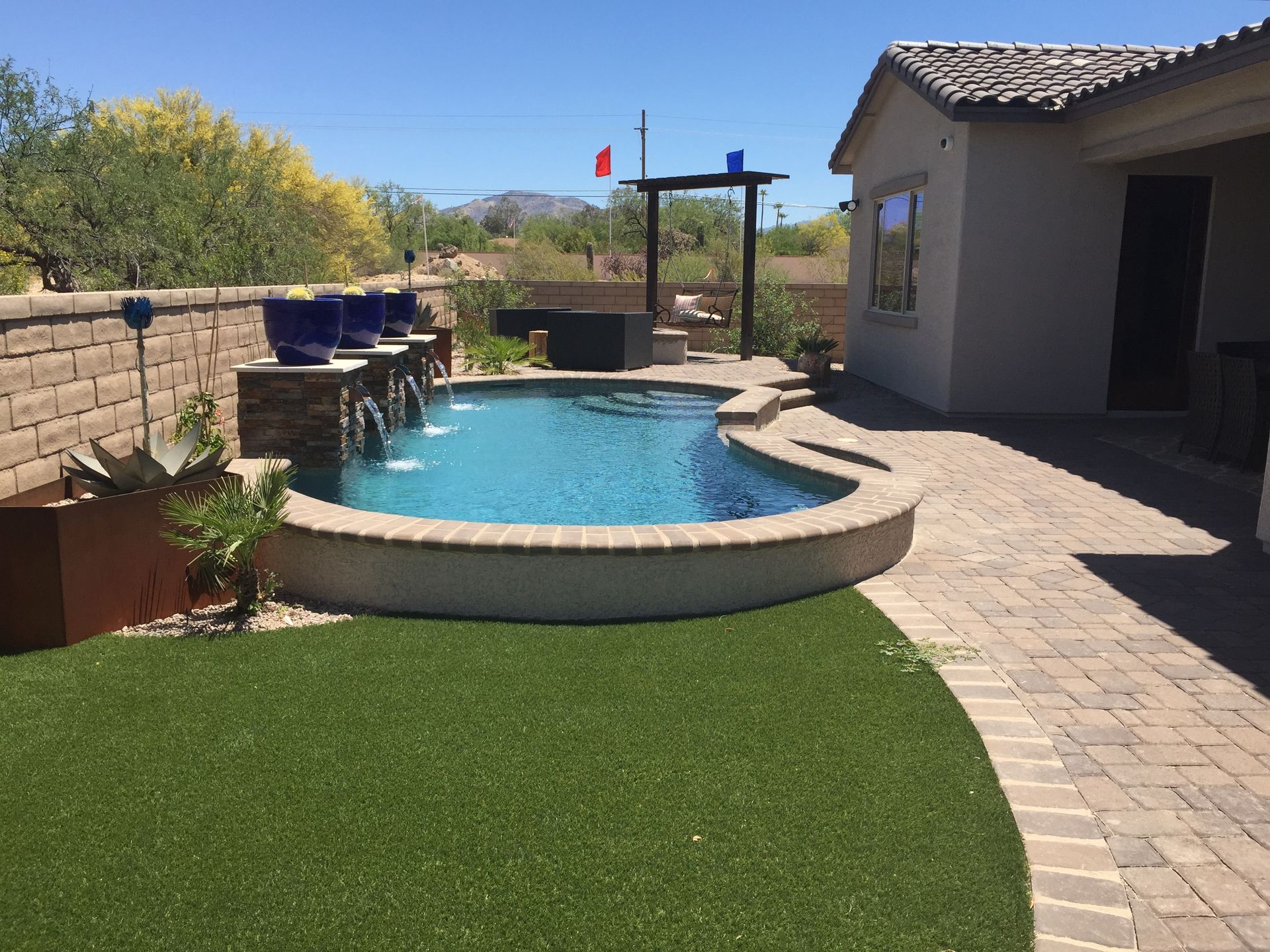 A swimming pool with a fountain in the backyard of a house