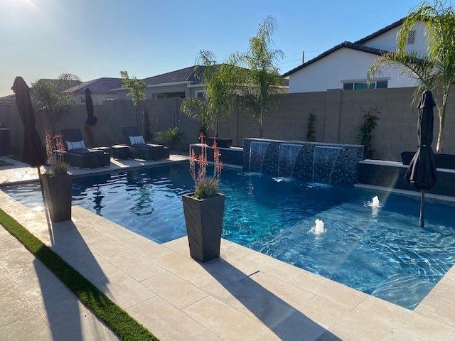 A large swimming pool with a waterfall in the backyard