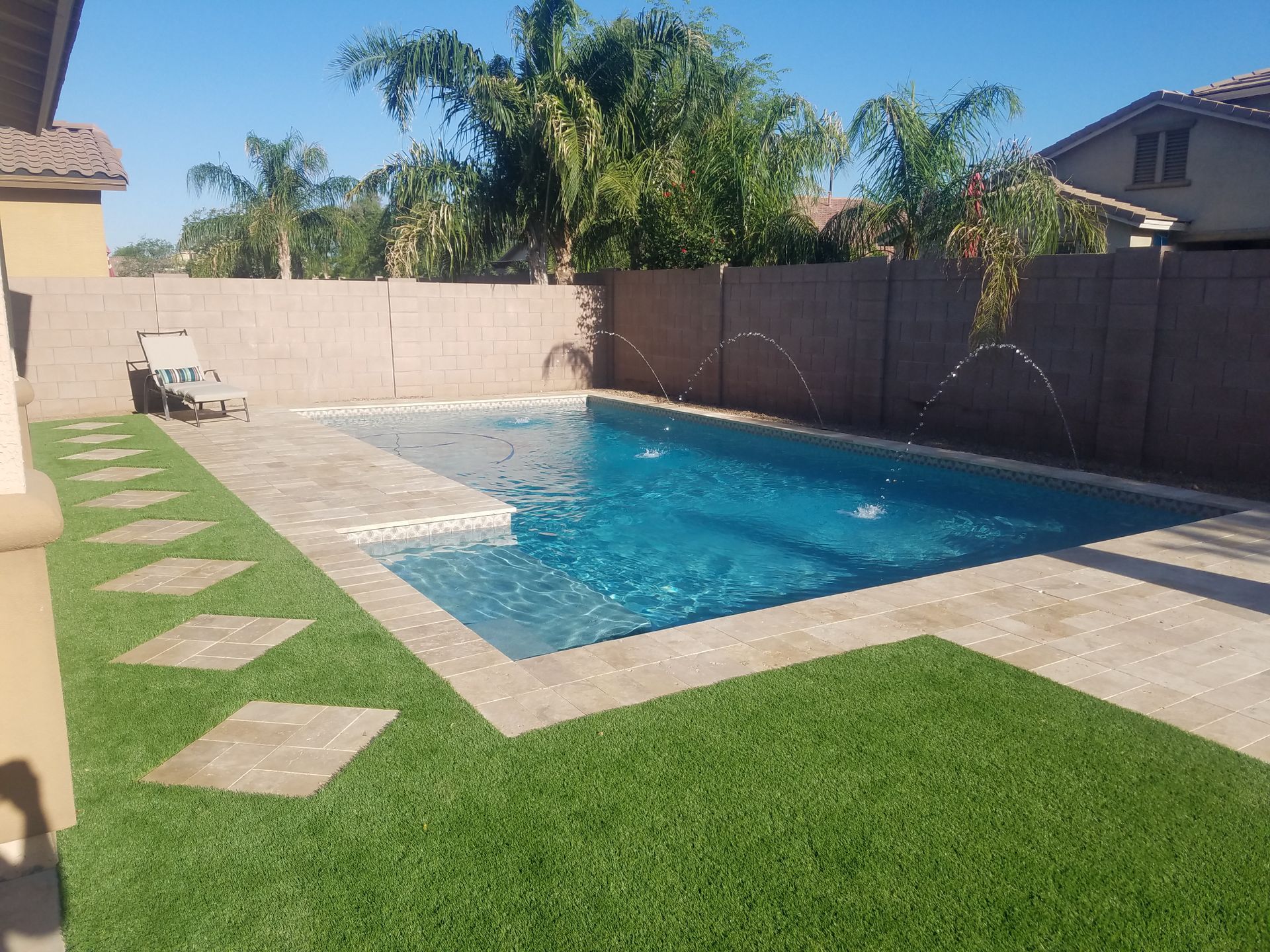 A large swimming pool is surrounded by a lush green lawn