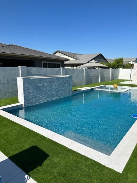 A large swimming pool in a backyard with a house in the background