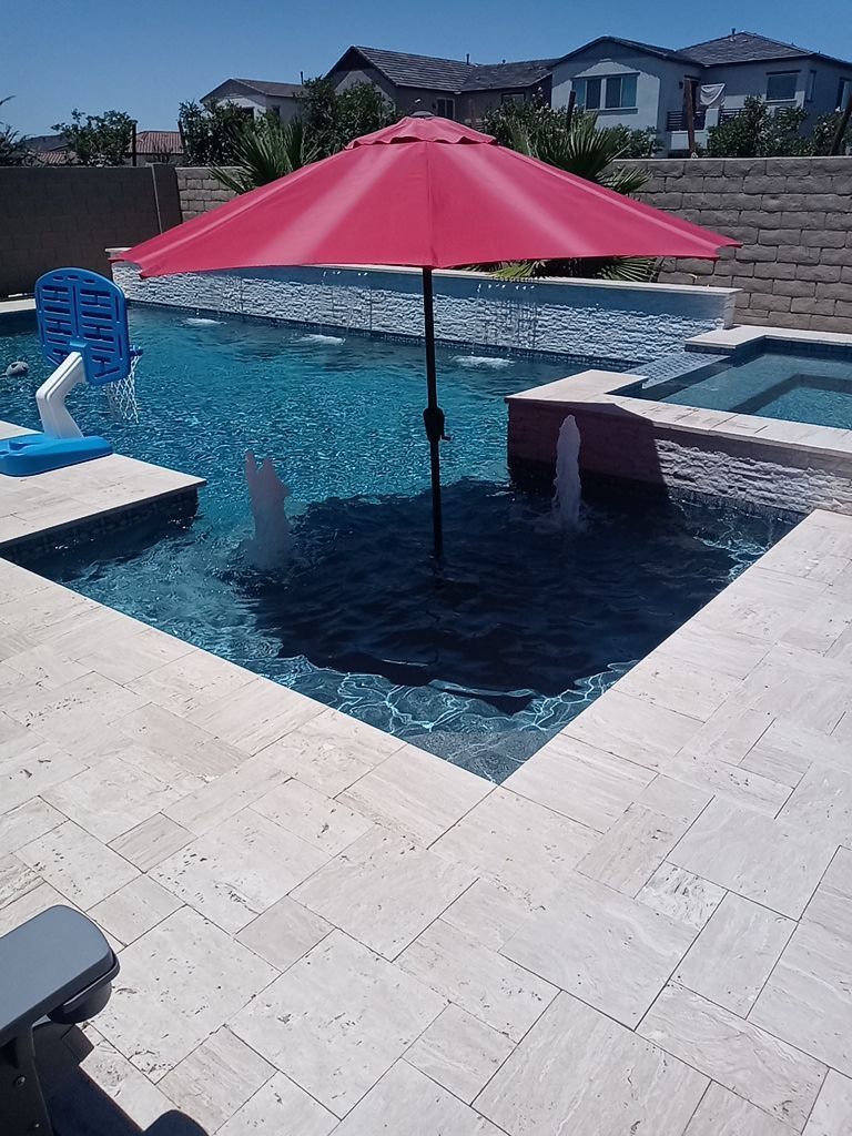 A red umbrella is sitting in the middle of a swimming pool.