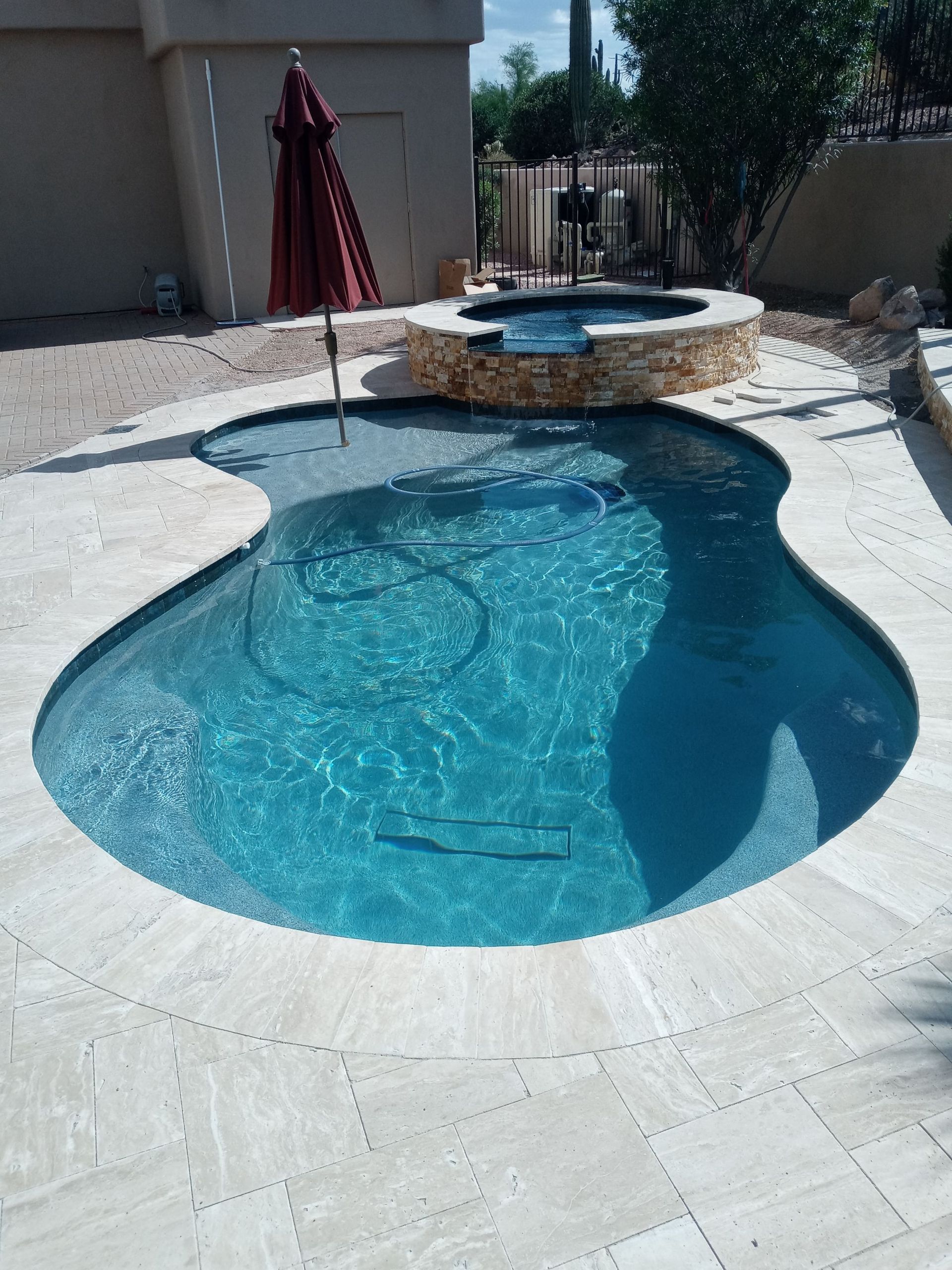 A large swimming pool with a red umbrella in the middle
