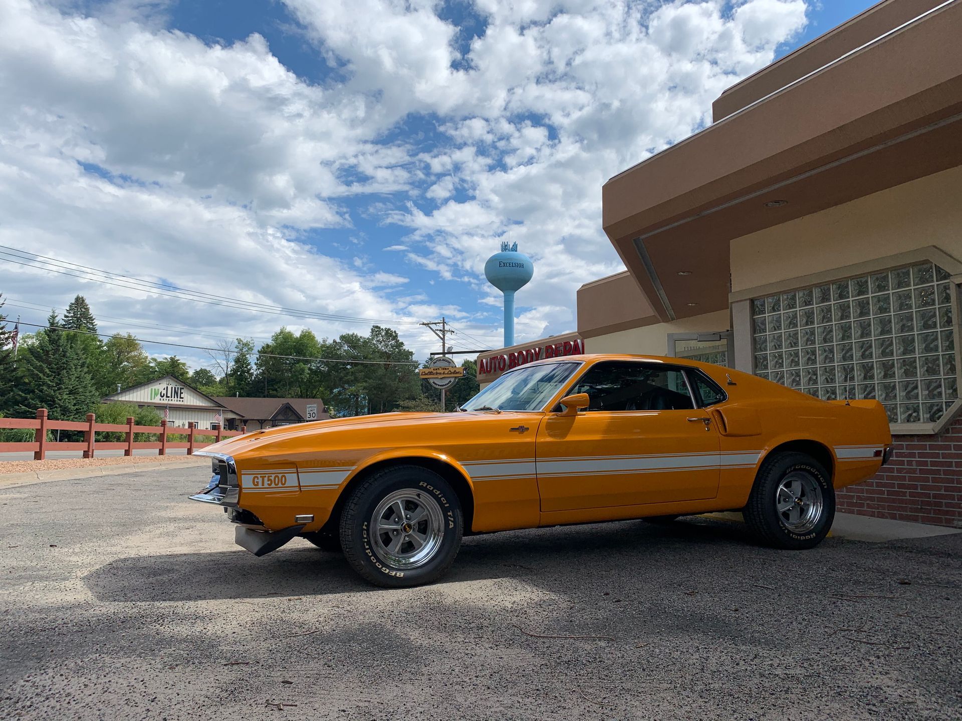 A yellow mustang is parked in front of a building