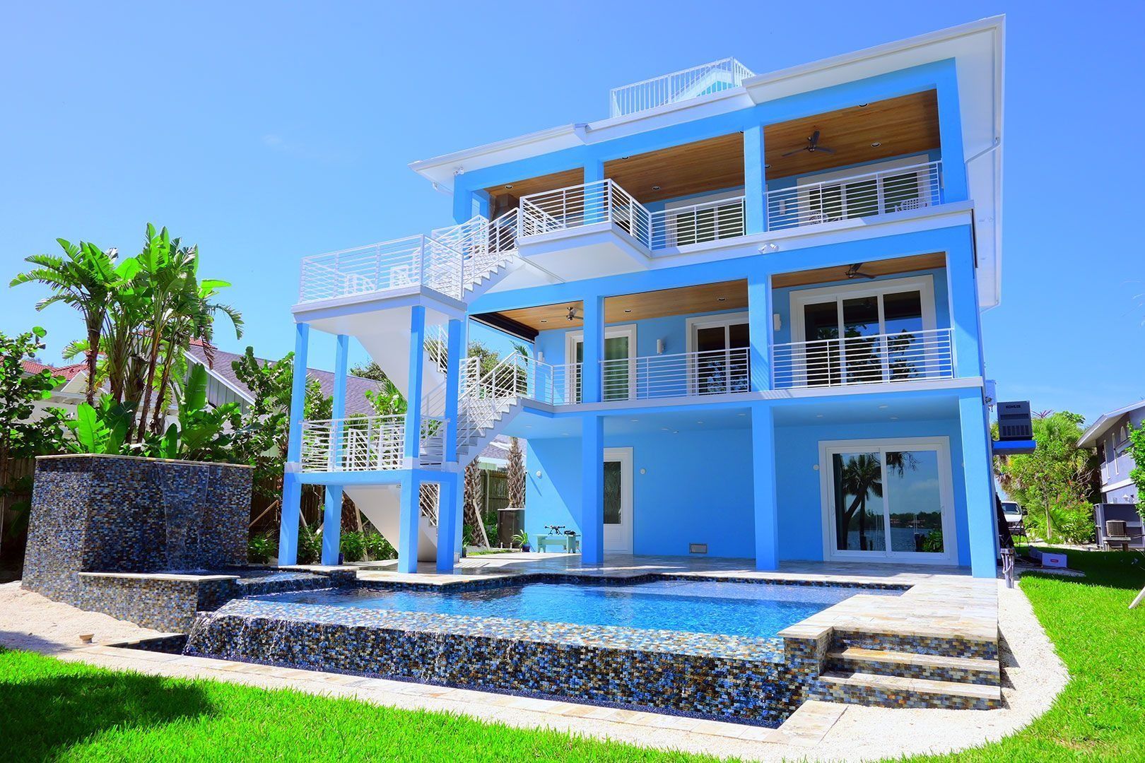Blue multi-story house with a pool and waterfront views.