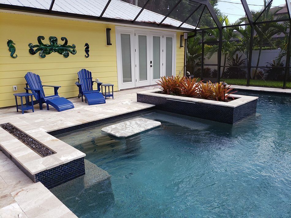 Poolside patio with blue chairs, pool, and a yellow building with seahorse art.
