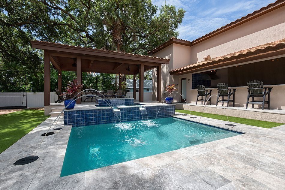 Backyard with a blue pool, a pergola, and an outdoor bar.