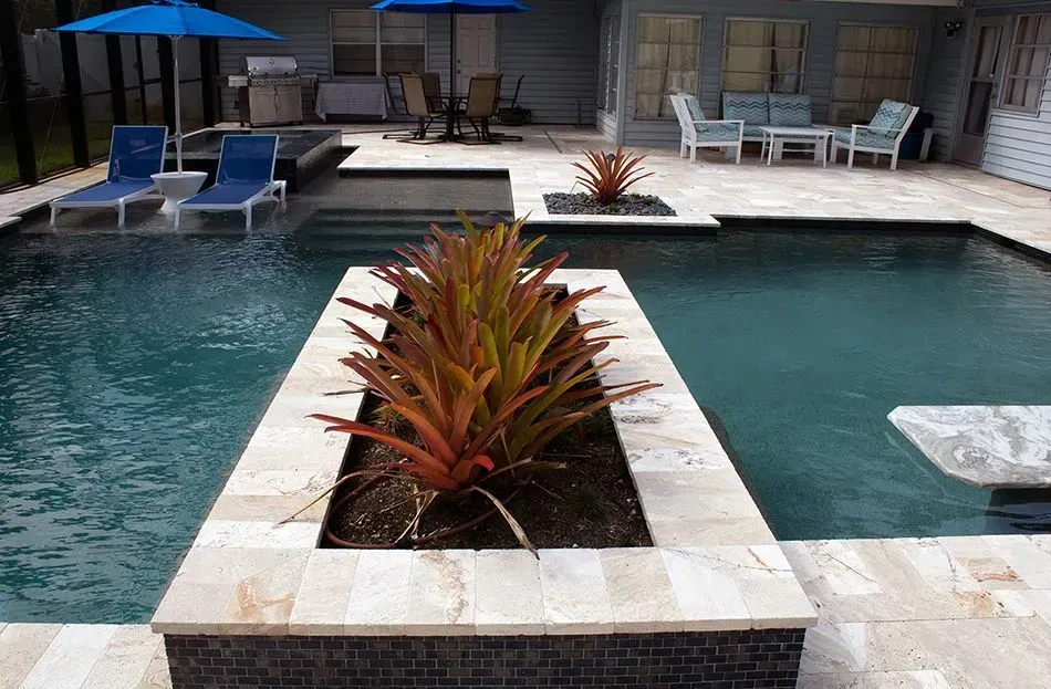 Pool with plants in planters, lounge chairs, and outdoor seating area.
