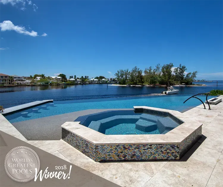 Pool with infinity edge, built-in spa, water view. Blue sky, sunny day.  