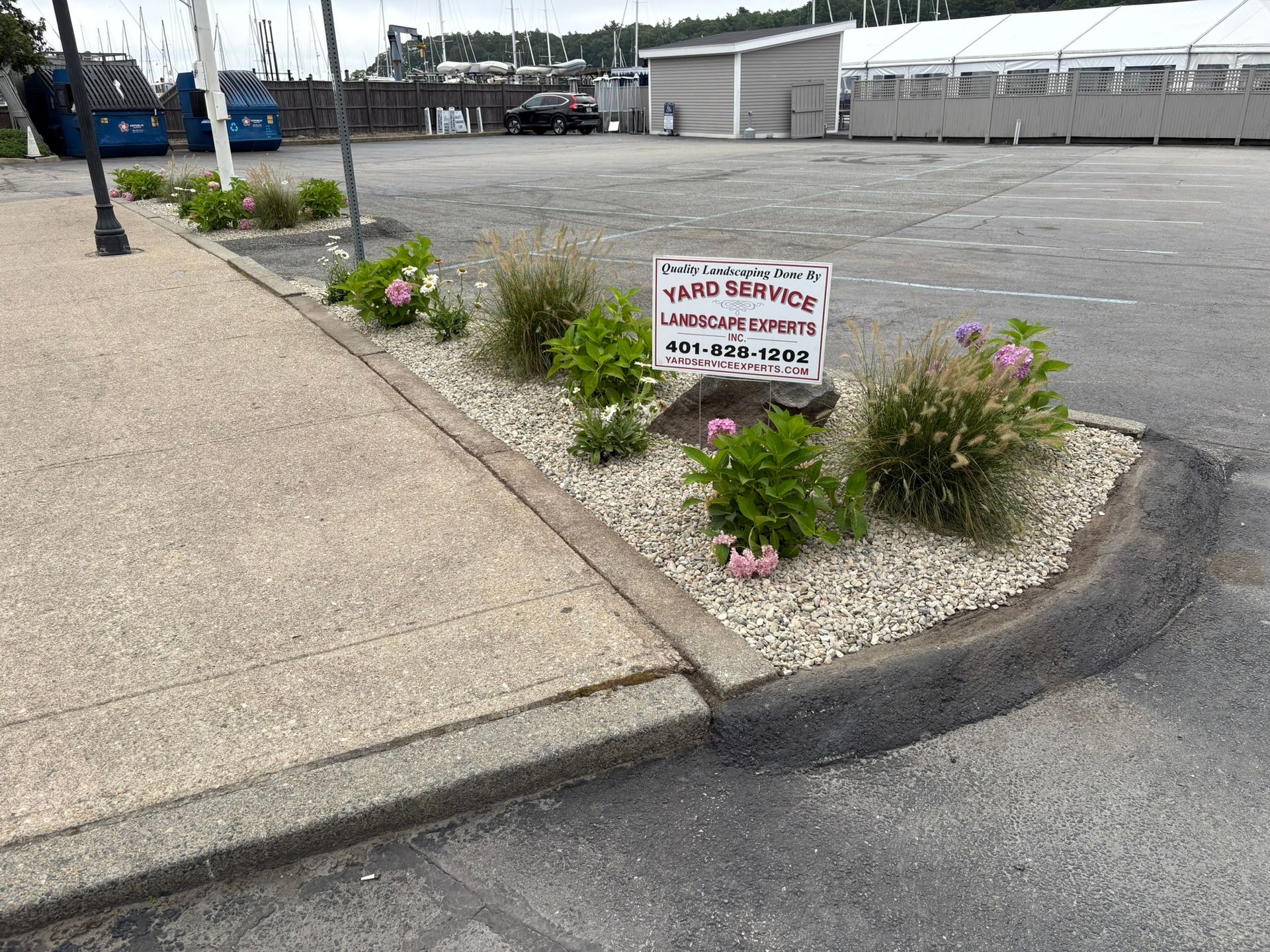 Flowerbed with sign in a parking lot.
