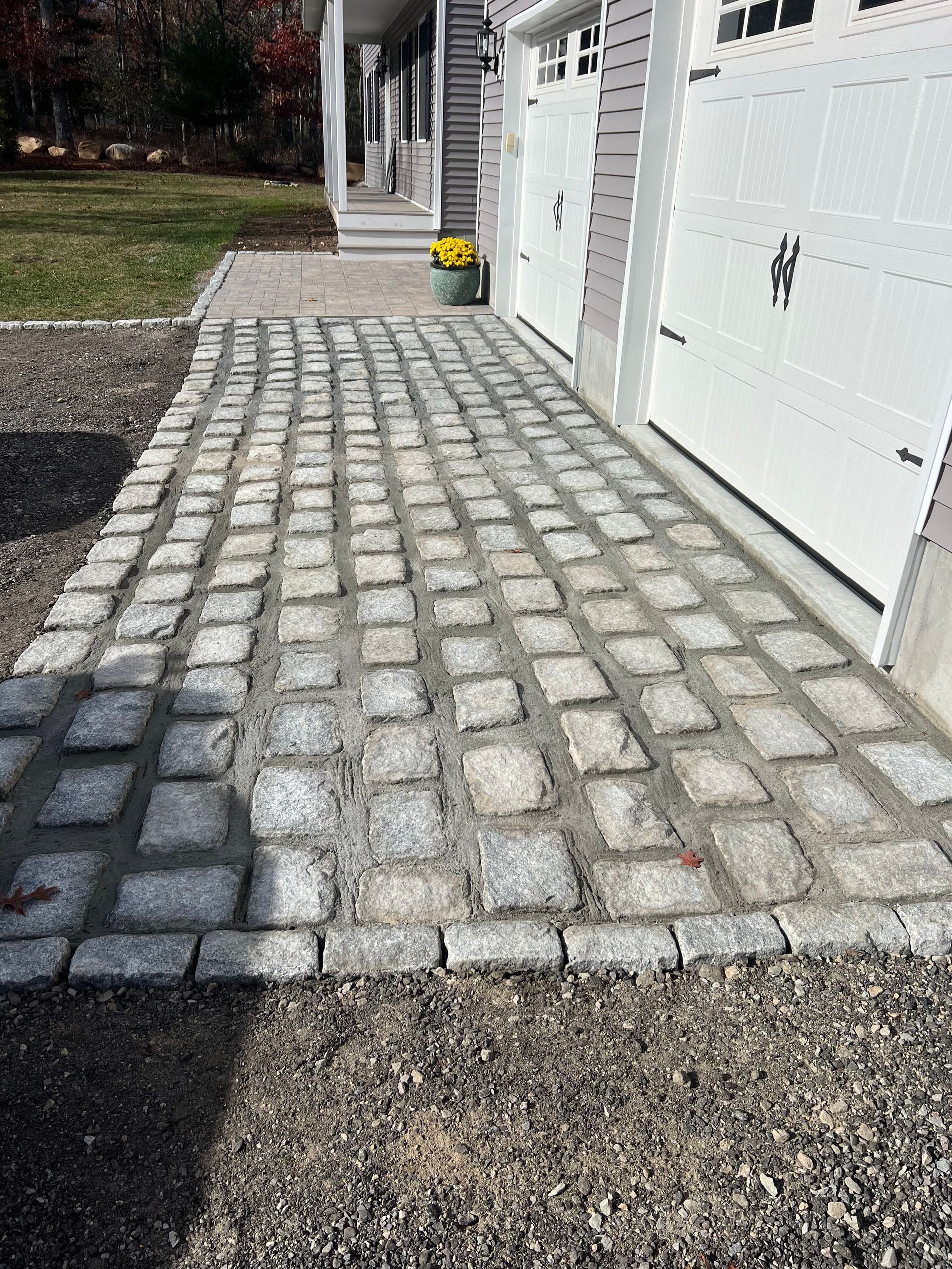 A cobblestone walkway leading to a garage and a house